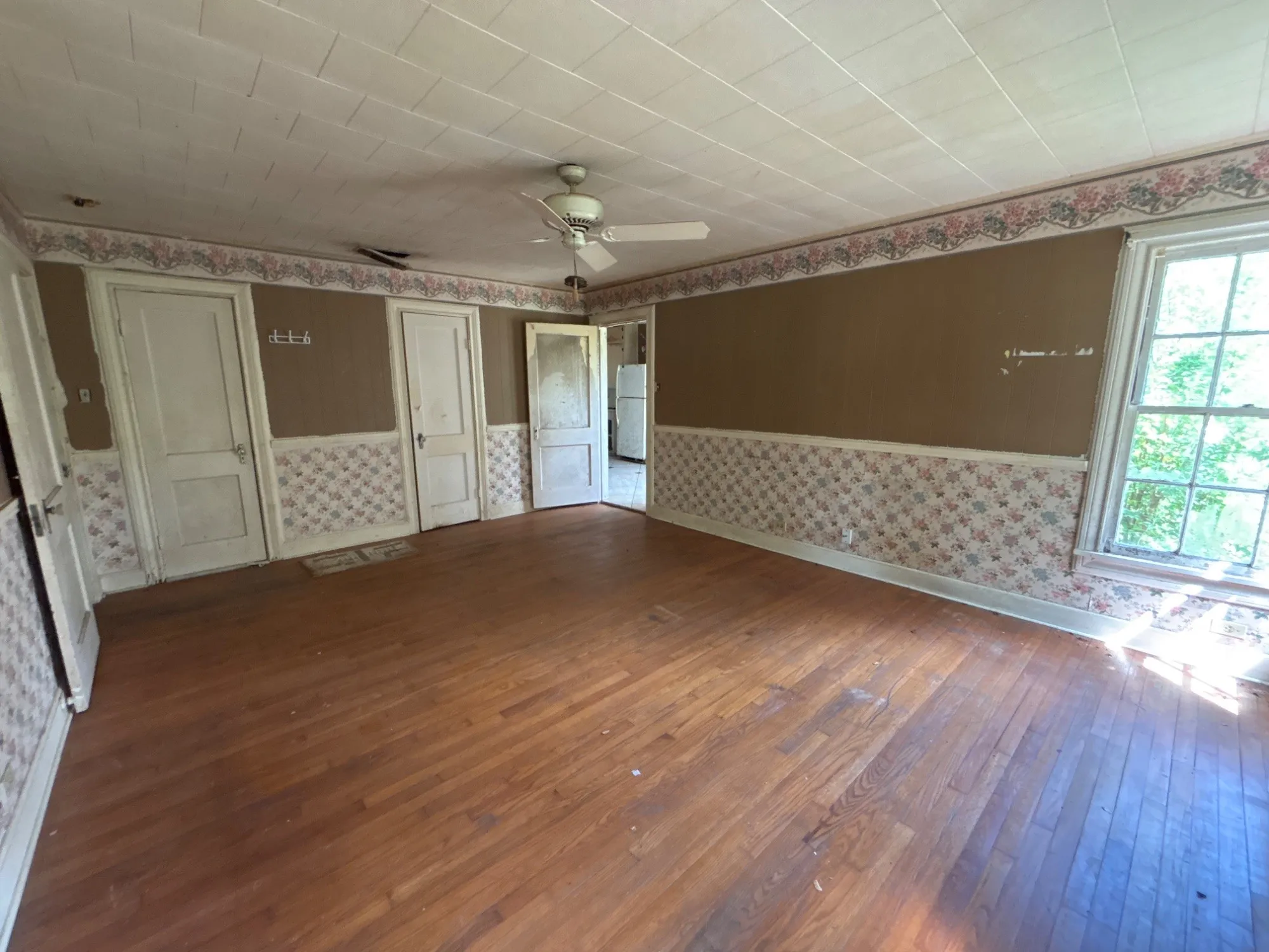 Versatile flex living space featuring original wood flooring, neutral two-tone walls, and natural window light.