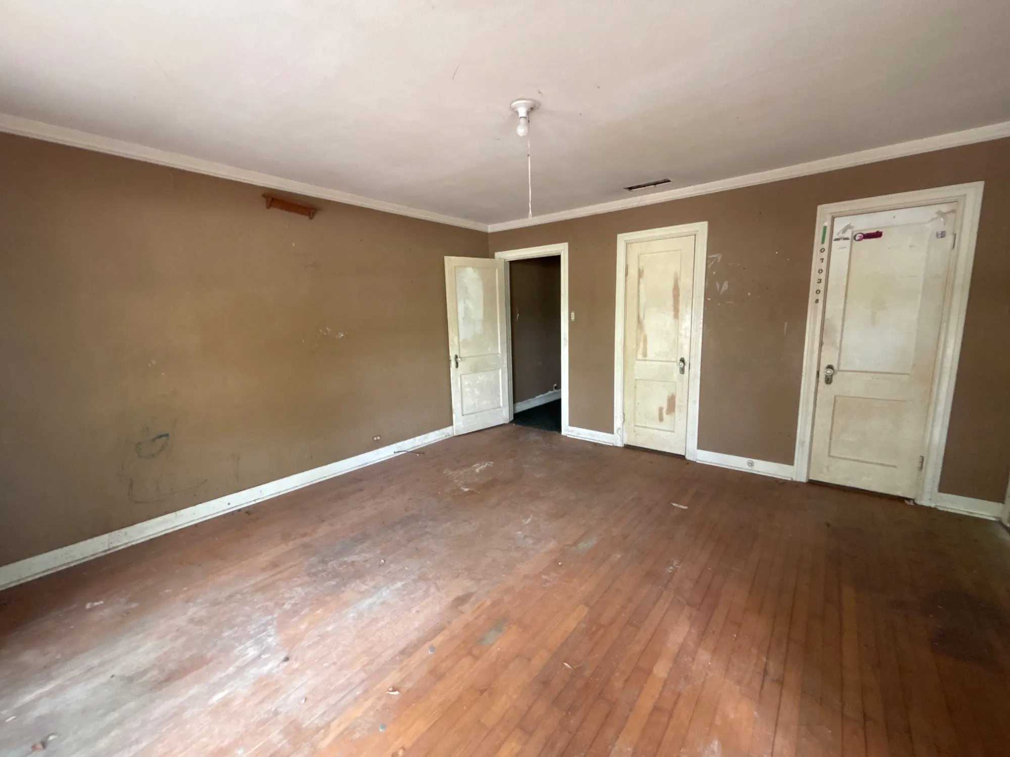 Spacious bedroom featuring wood flooring, multiple windows, double closet doors, and ceiling fan.
