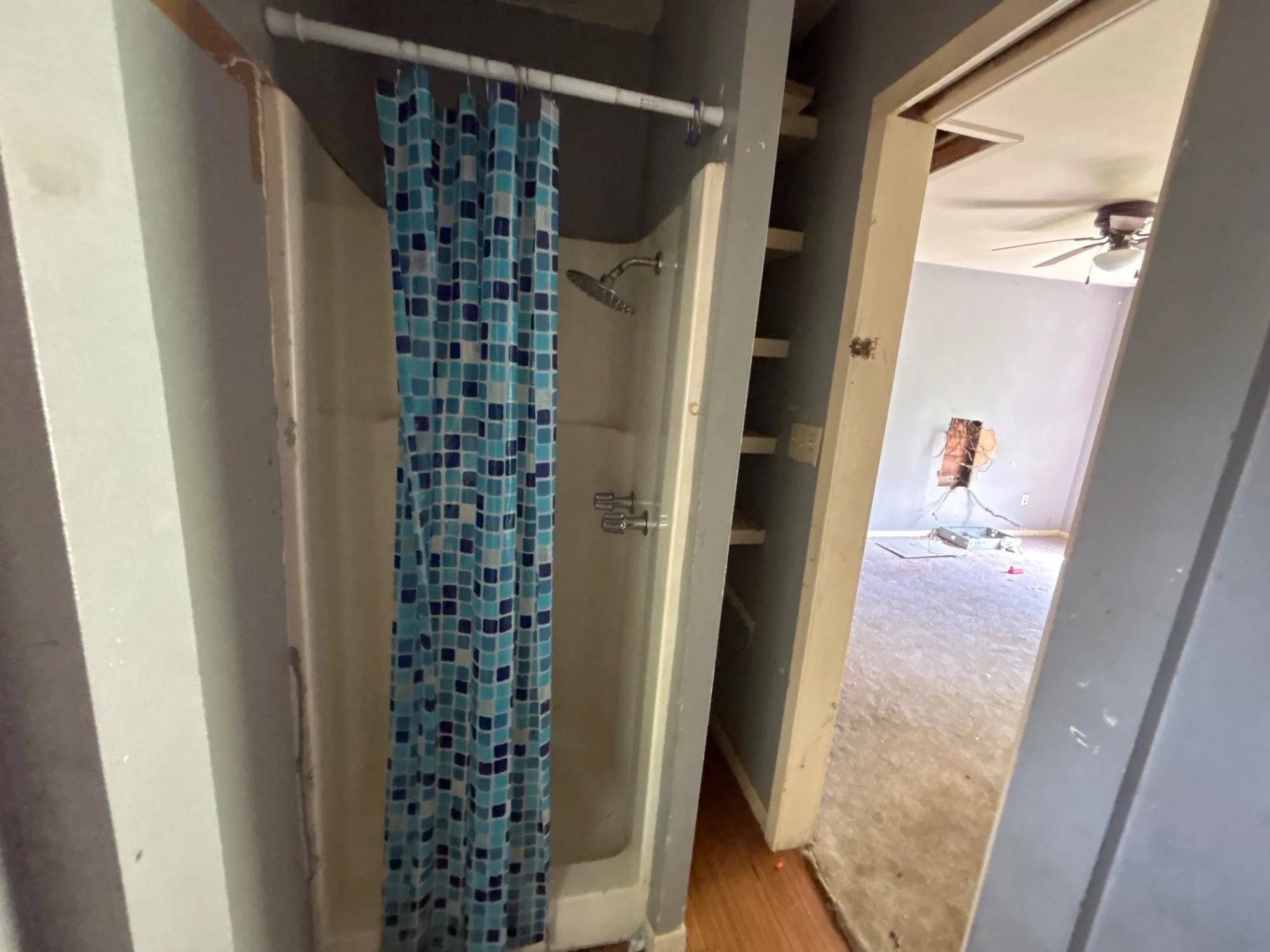 Walk-in shower enclosure featuring patterned shower curtain and doorway transition.