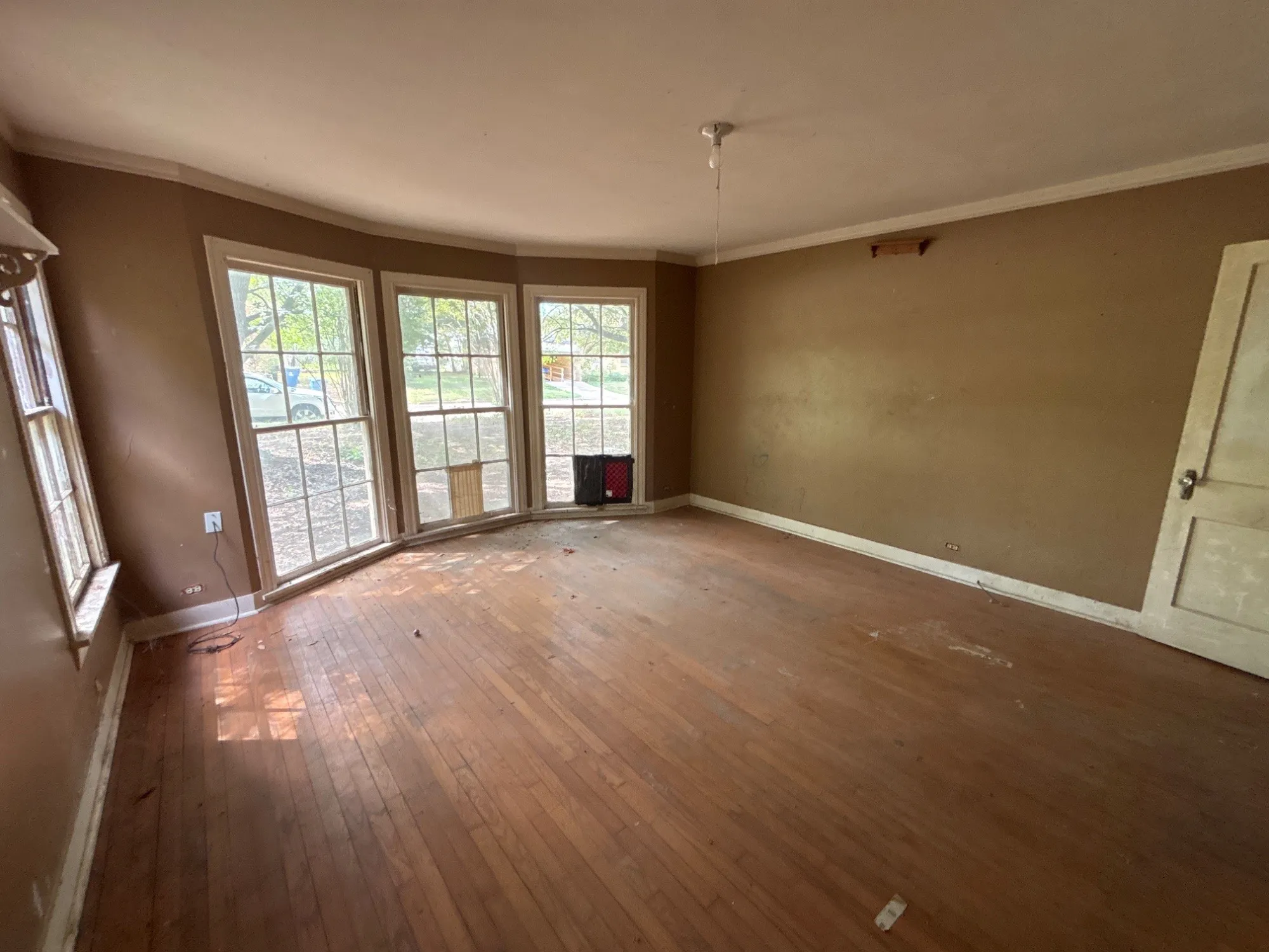 Open family room layout with wood floors, ceiling fan, and bright bay window feature.