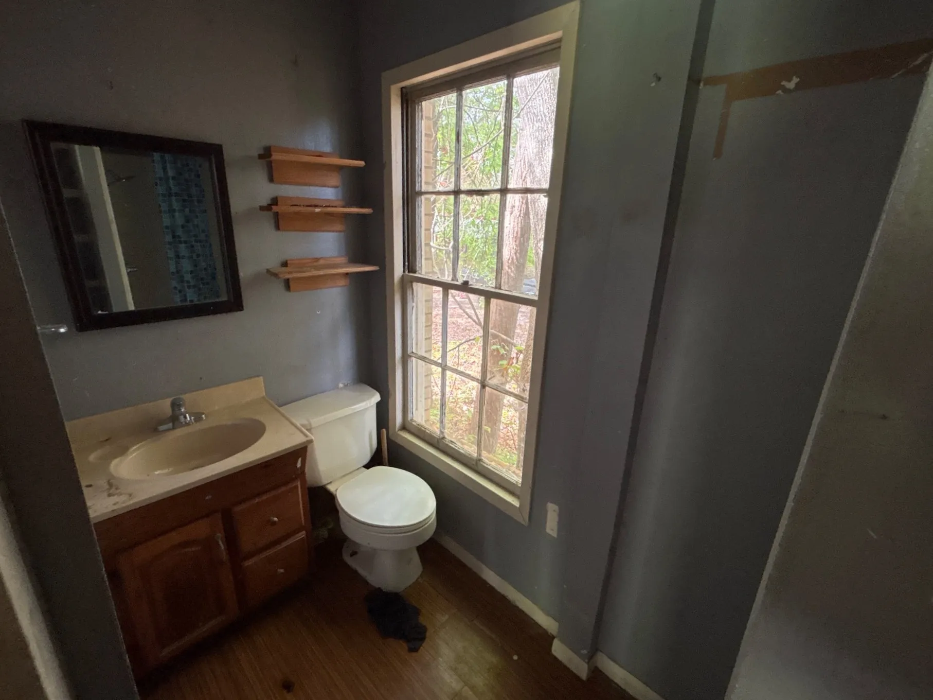 Alternate view of the bathroom vanity area displaying wall storage shelves and window placement.