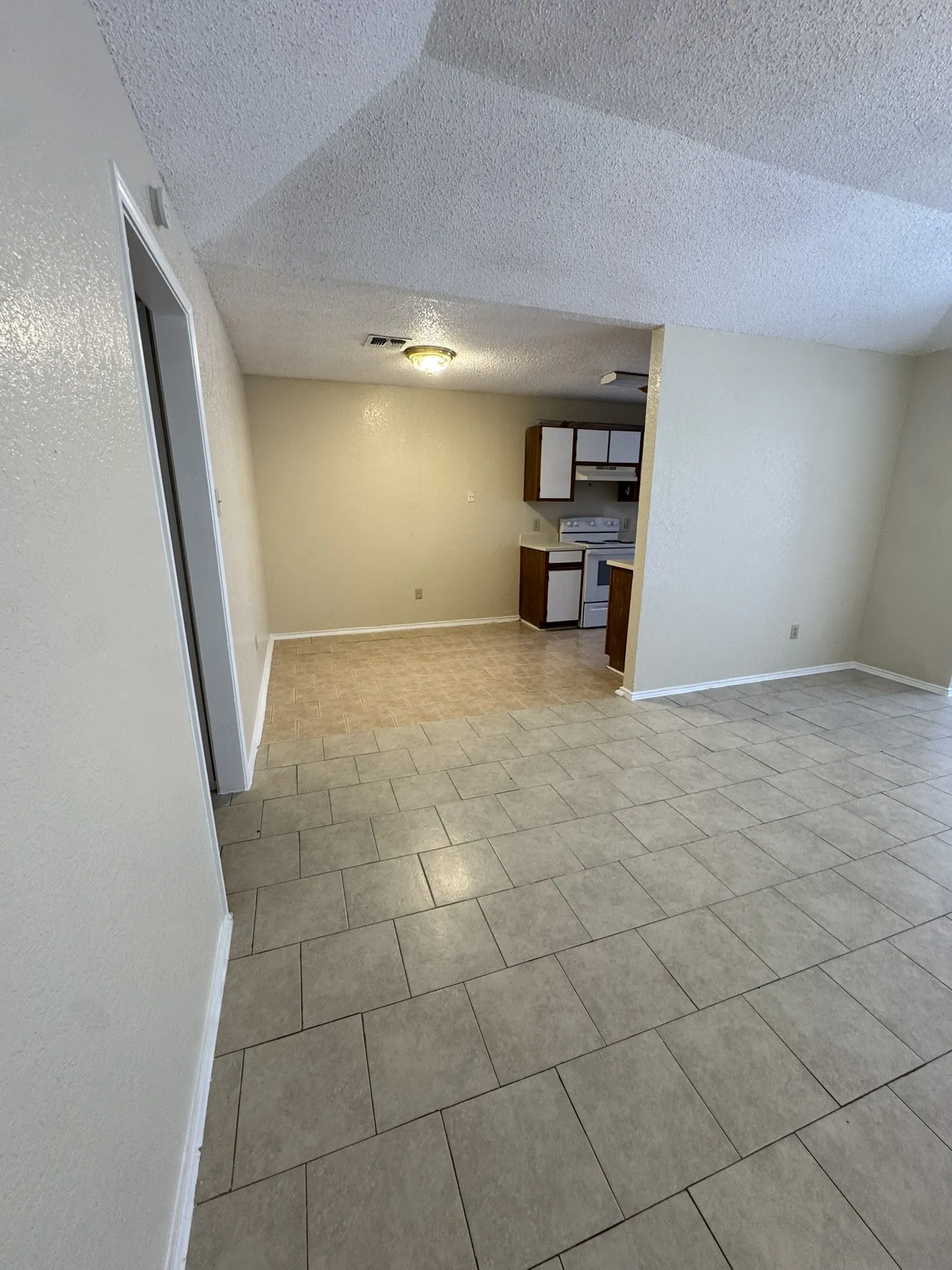 Tile flooring throughout the main living areas and kitchen, featuring white cabinetry and a built-in range