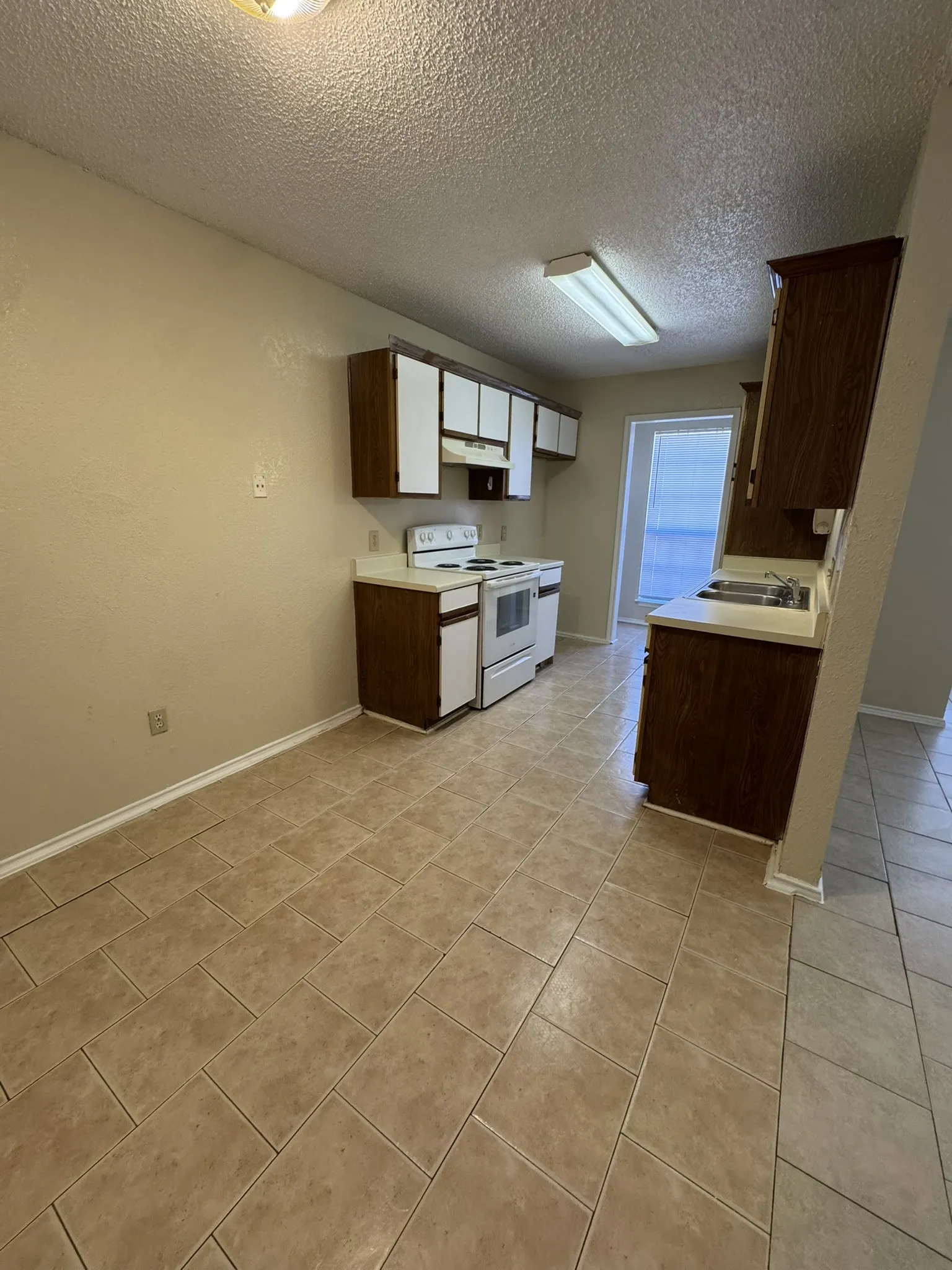 Kitchen featuring tile flooring, white appliances, laminate countertops, and wood-finish cabinetry