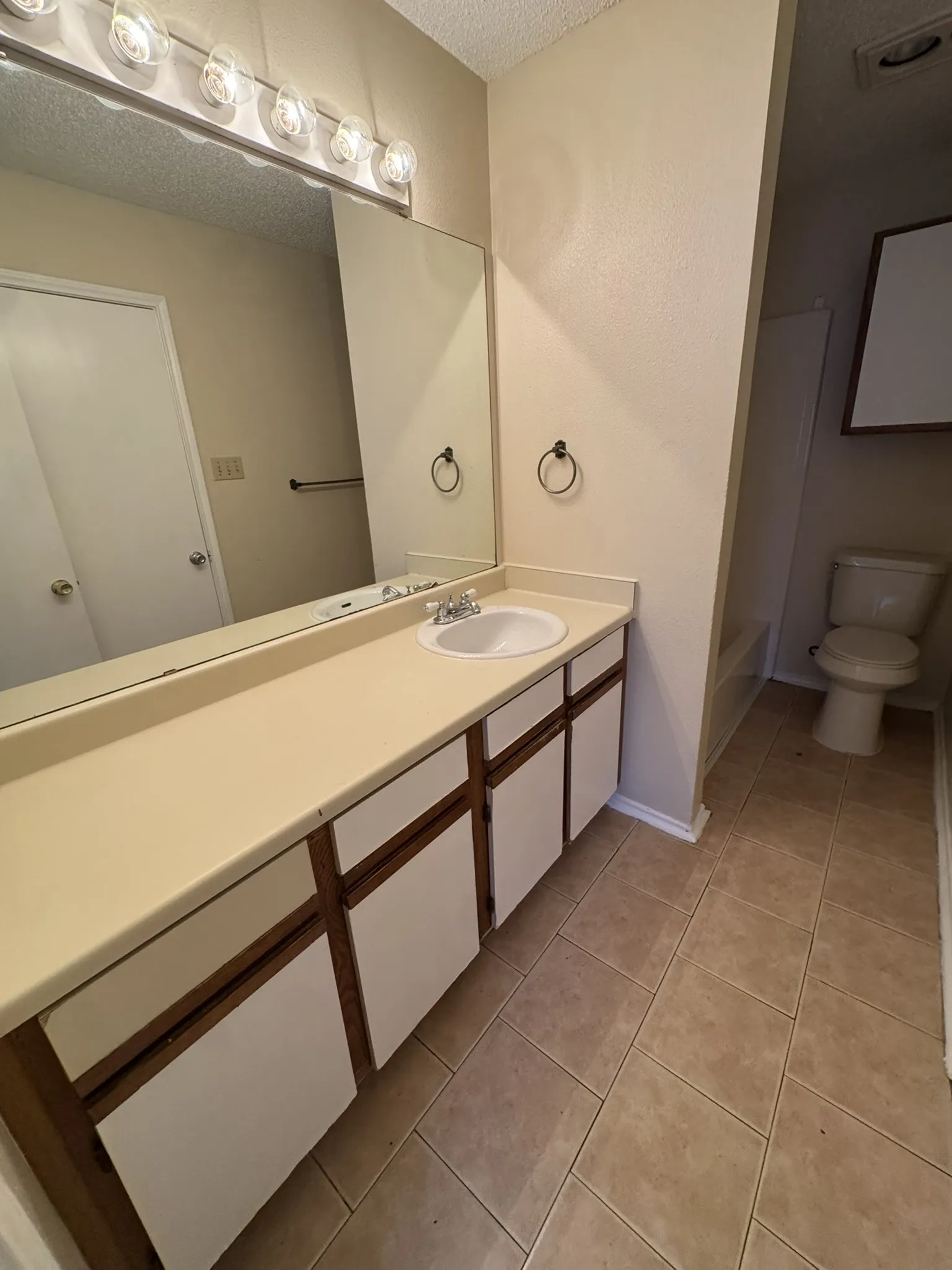 Bathroom featuring a vanity with an integrated sink, a large wall-mounted mirror, and tile flooring