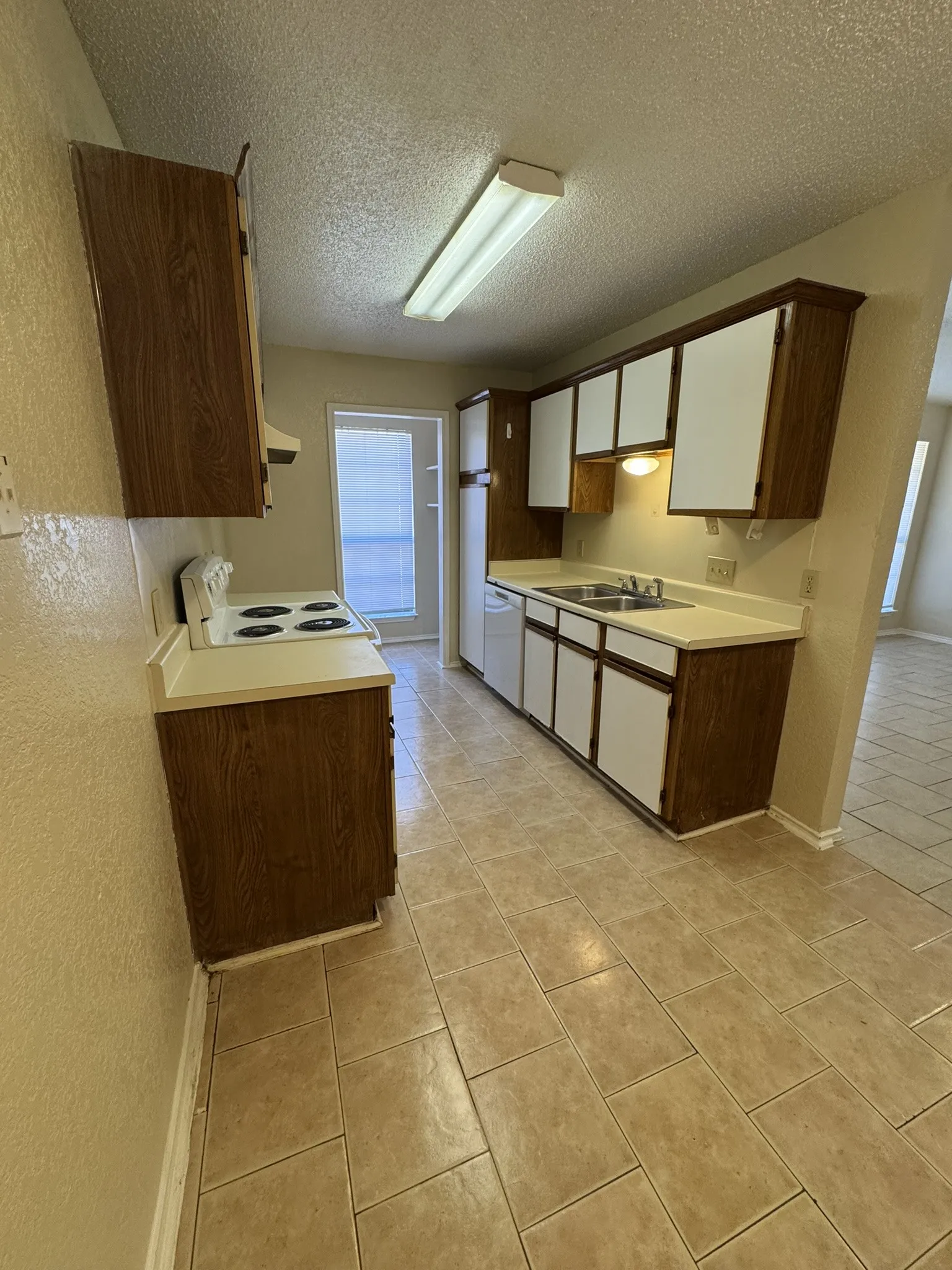 Kitchen featuring tile flooring, wood-finish cabinetry, and a double basin sink
