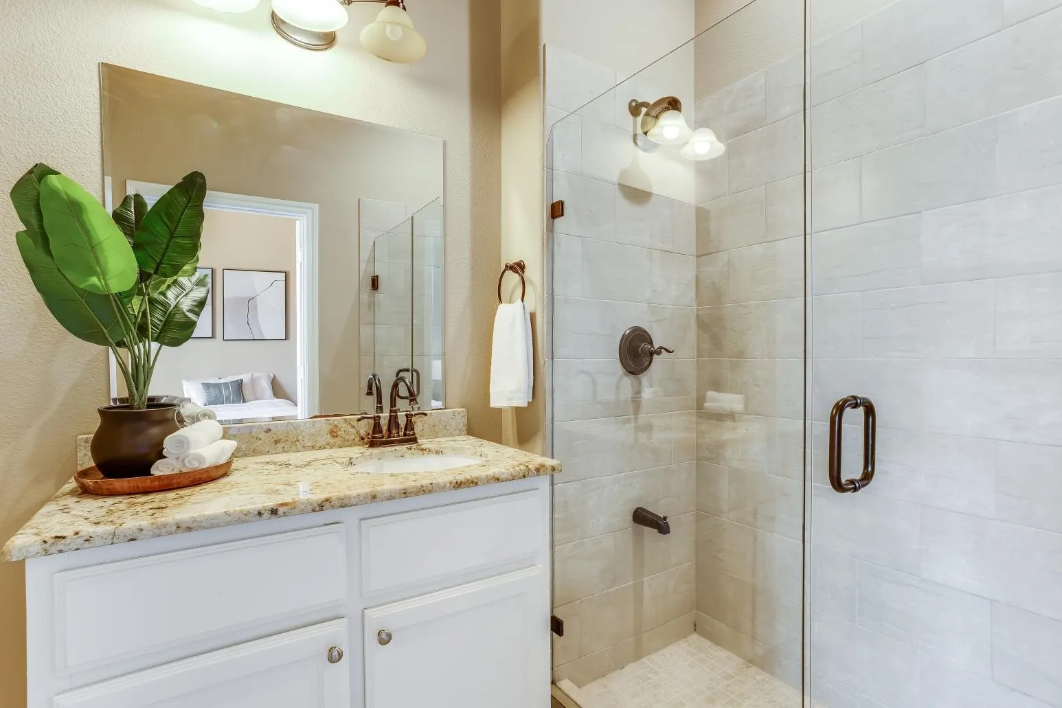 White vanity cabinetry with a light-colored countertop, an undermount sink, and a bronze-finish faucet