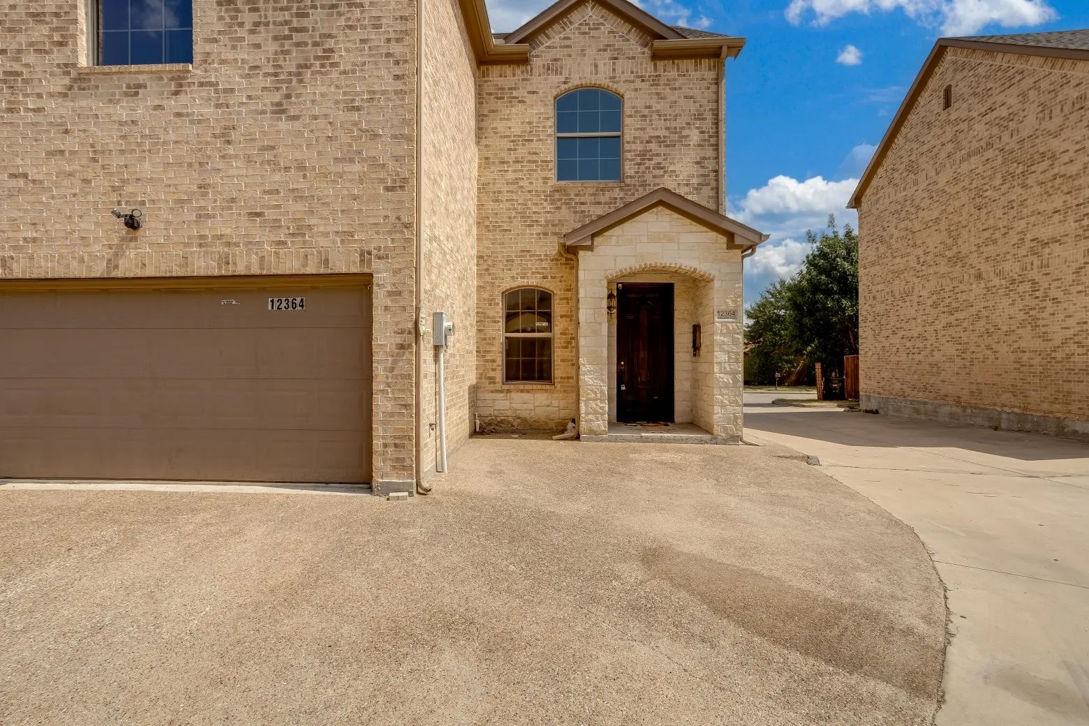 Brick exterior with stone accents, arched windows, and an integrated garage
