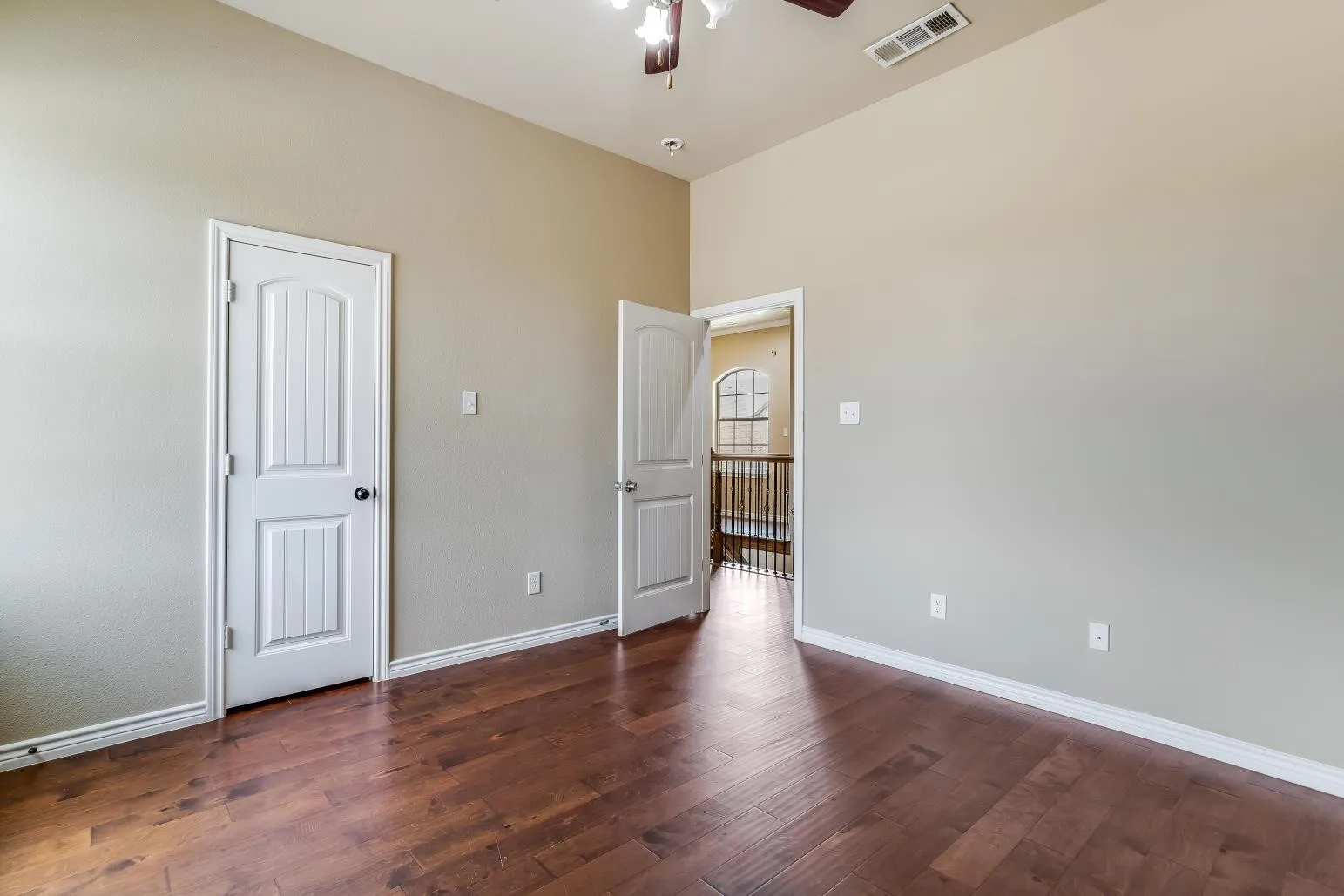 Vaulted ceiling, wood-finish flooring, paneled interior doors, and a ceiling fan