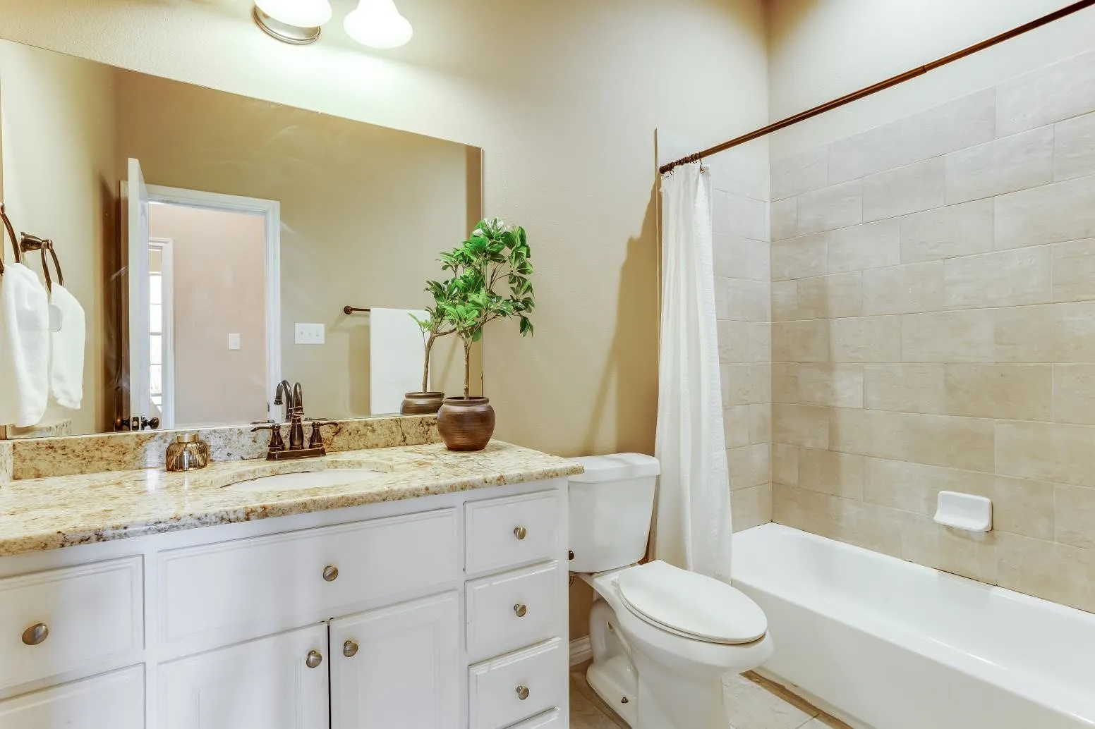 White vanity with brass-finish hardware, granite-style countertop, and integrated sink
