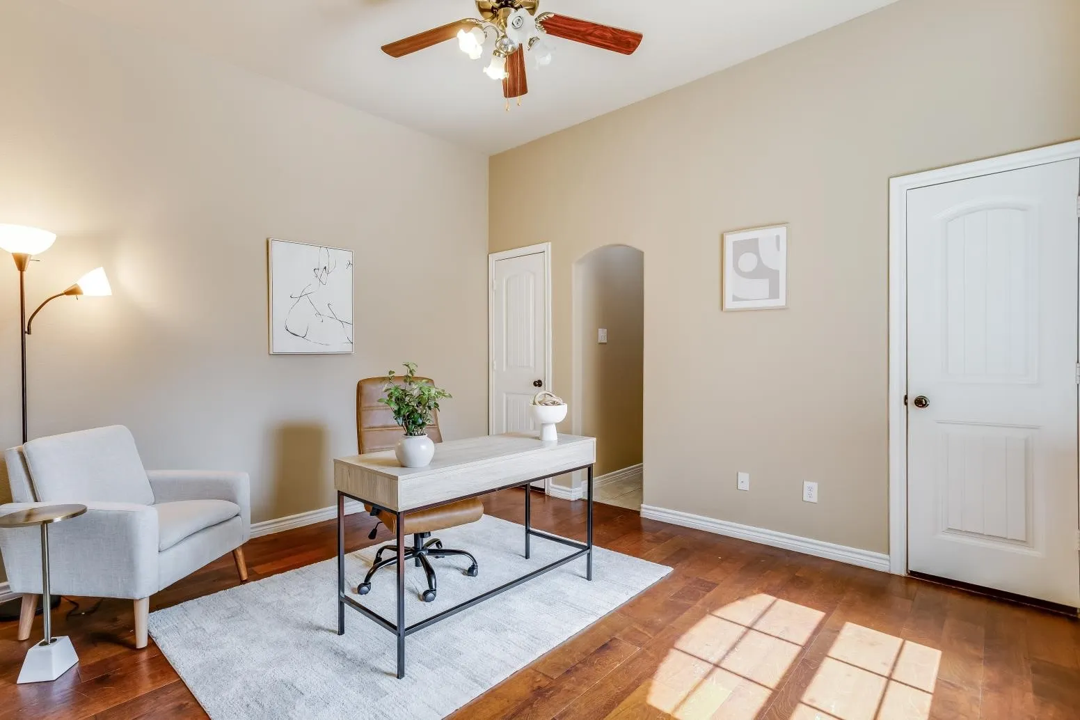 Vaulted ceiling with a ceiling fan, hardwood flooring, and an arched doorway