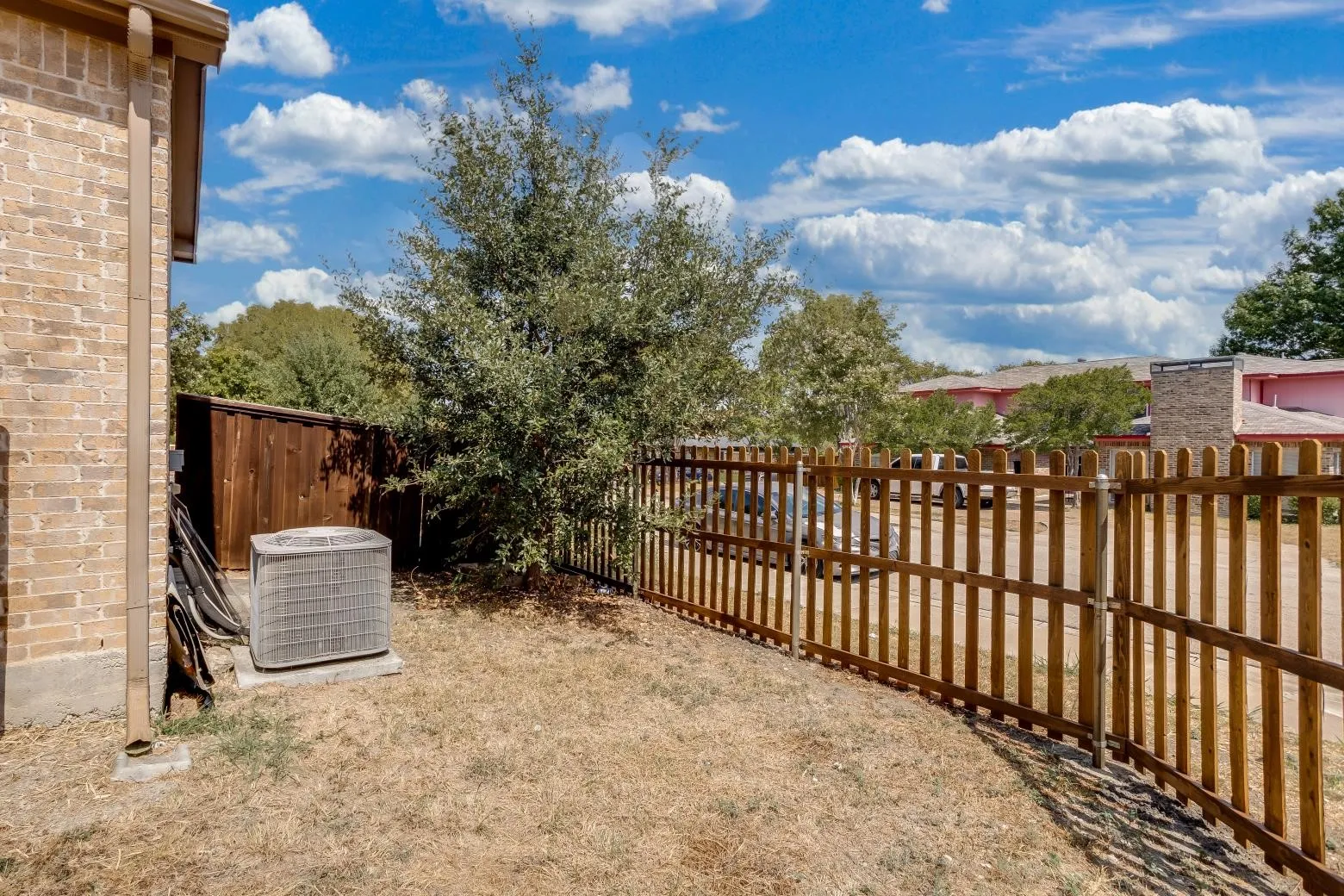 Brick exterior with a wooden privacy fence and a gated section