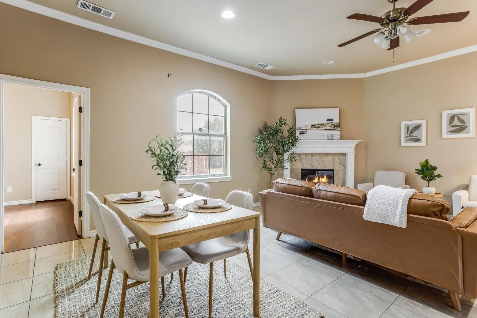 Living area featuring tile flooring, a fireplace with a stone surround, and crown molding