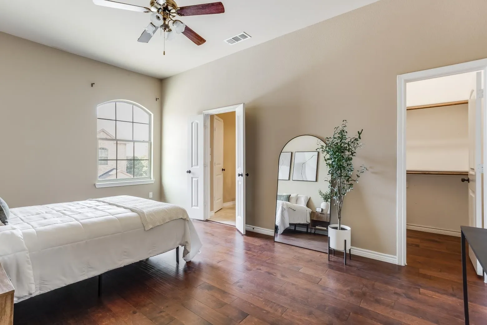 Vaulted ceiling with a ceiling fan, arched window, wood-finish flooring, and white trim