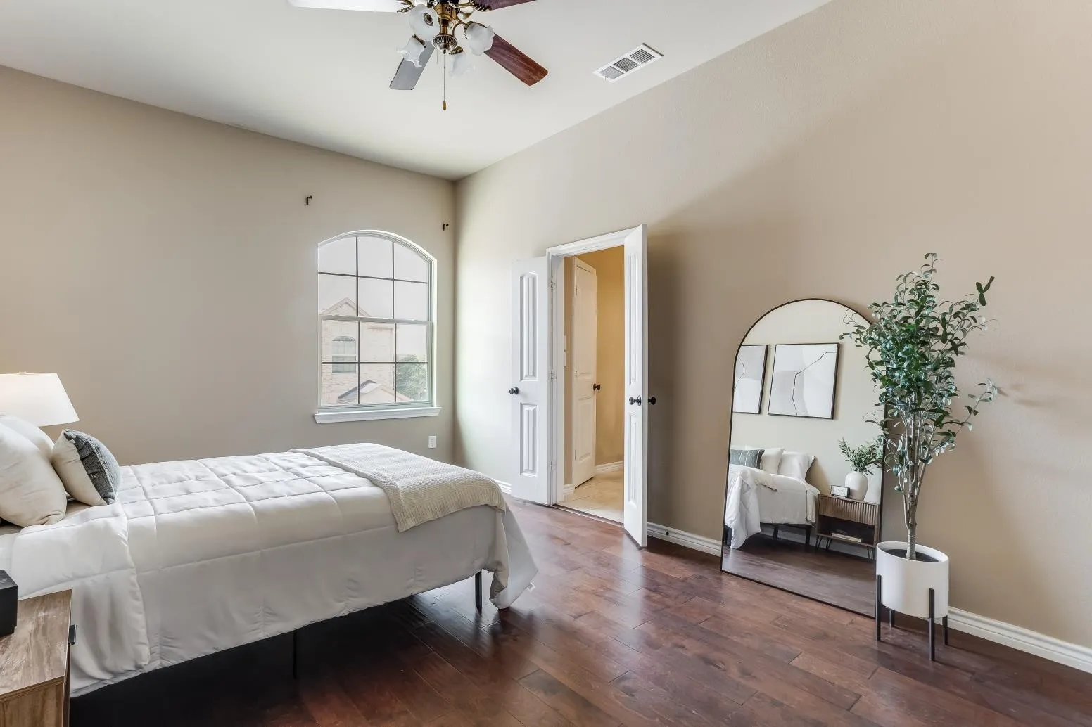 Vaulted ceiling with a ceiling fan, arched window, wood-finish flooring, and white paneled doors