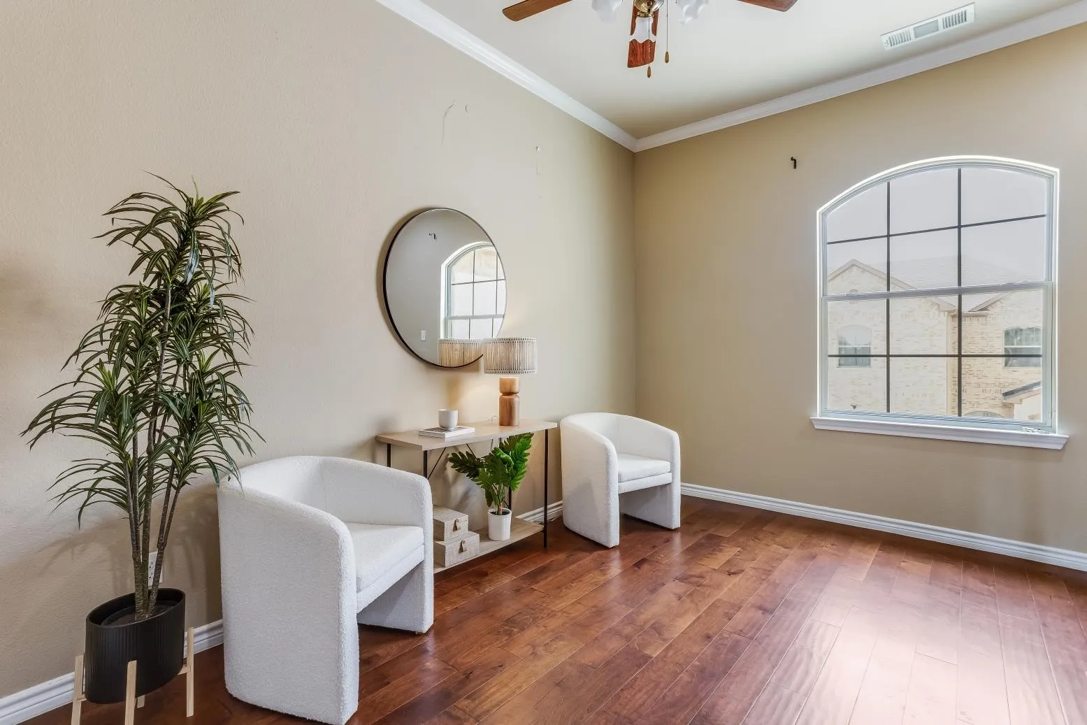 Hardwood flooring, crown molding, arched window with grid, and ceiling fan with light fixture