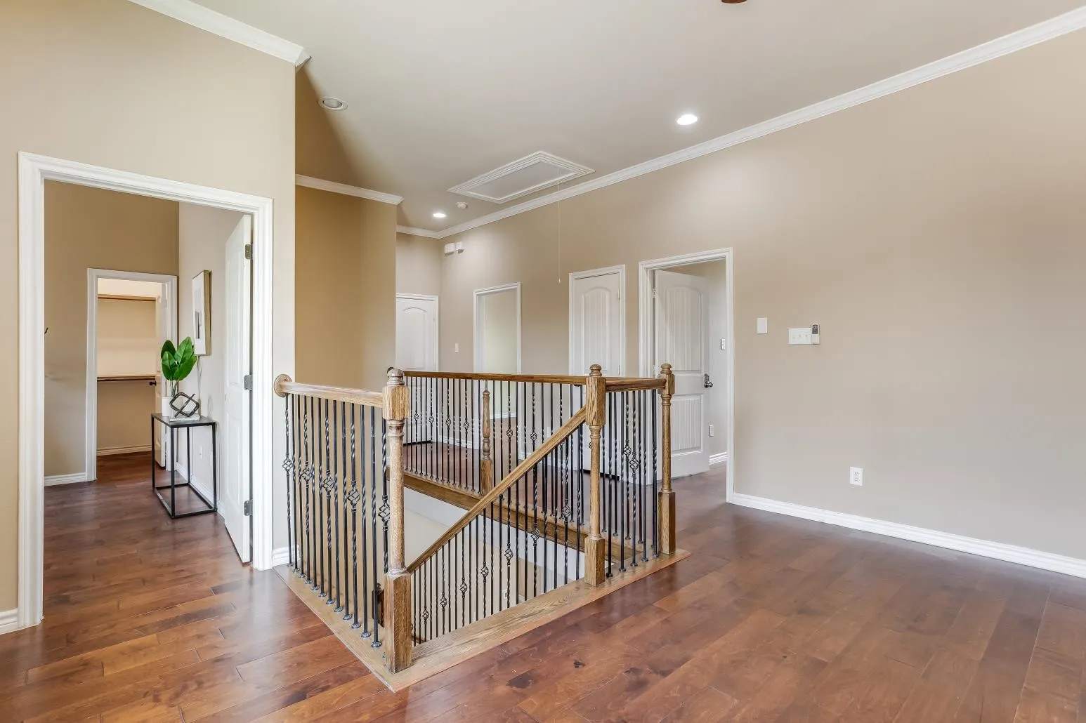 Hardwood-finish flooring throughout, crown molding, recessed lighting, wood staircase with wrought iron balusters, and paneled doors
