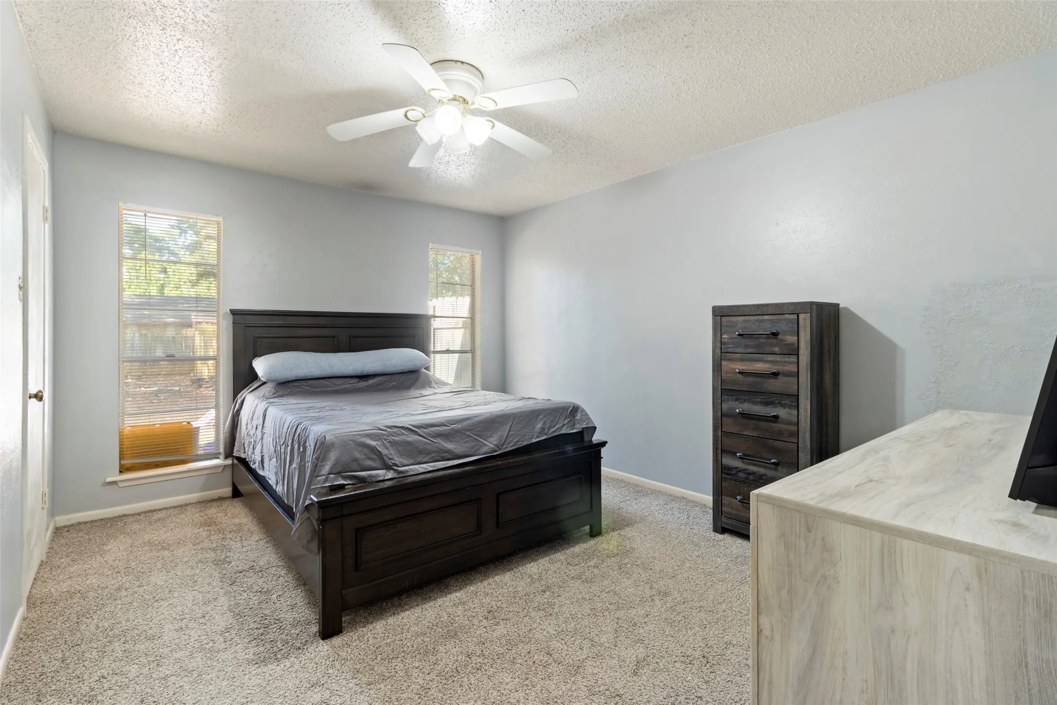 Carpeted flooring, vaulted ceiling, and two windows provide natural illumination