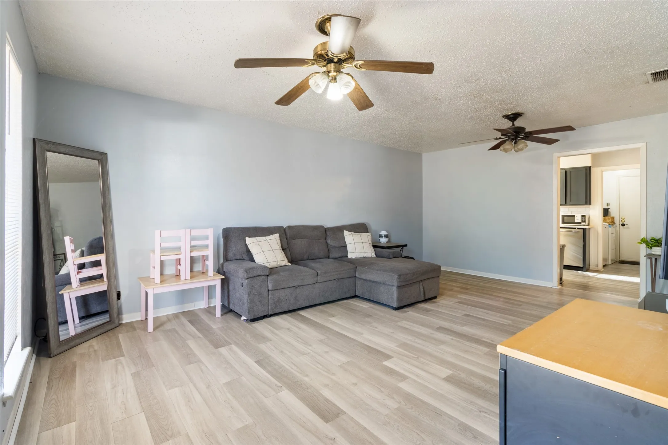 Wood-finish flooring throughout, light-toned walls, and multiple ceiling fans