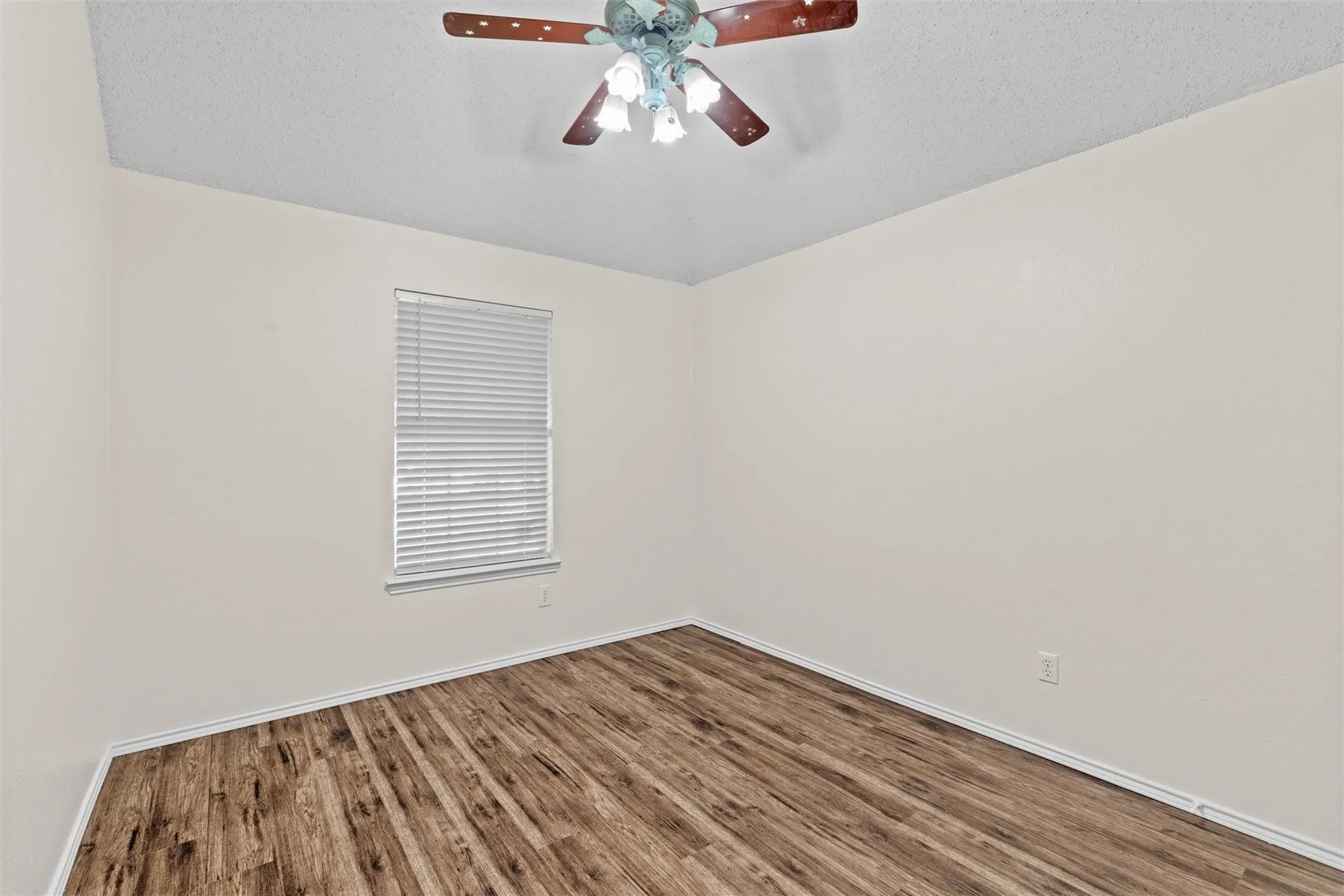 Wood-finish flooring, single window with blinds, and ceiling fan with integrated lighting