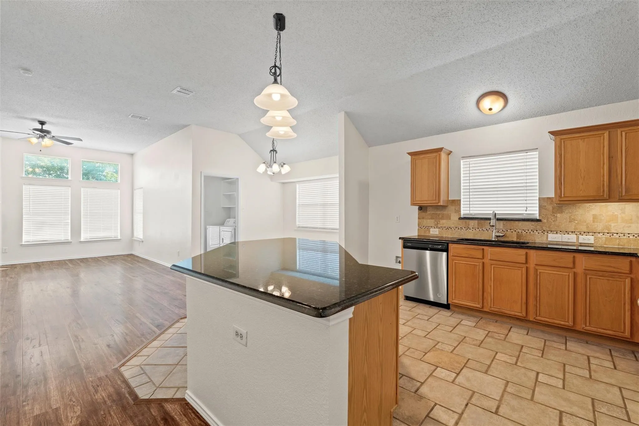 Kitchen featuring wood cabinetry, dark countertops, a tile backsplash, and stainless steel appliances