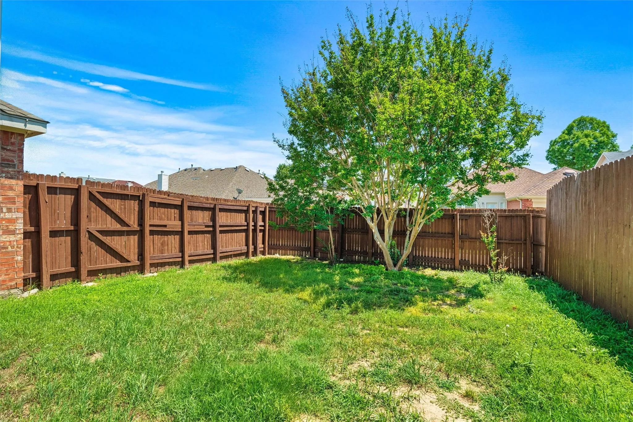 Fenced backyard with established tree and brick exterior
