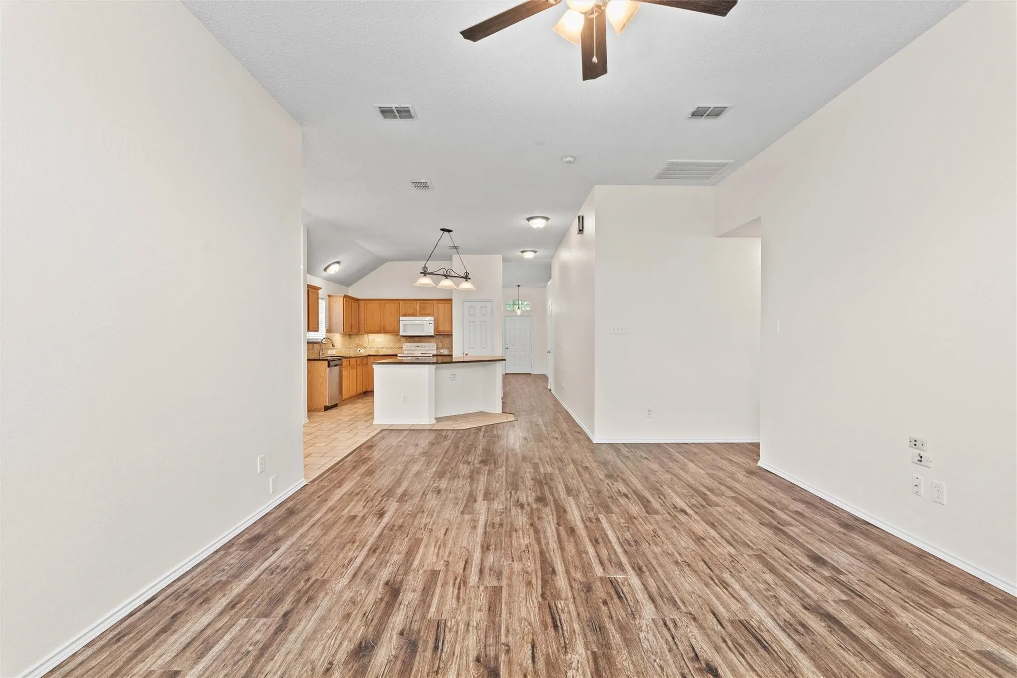 Wood-finish flooring throughout, vaulted ceiling in kitchen, recessed lighting, ceiling fan, and white walls