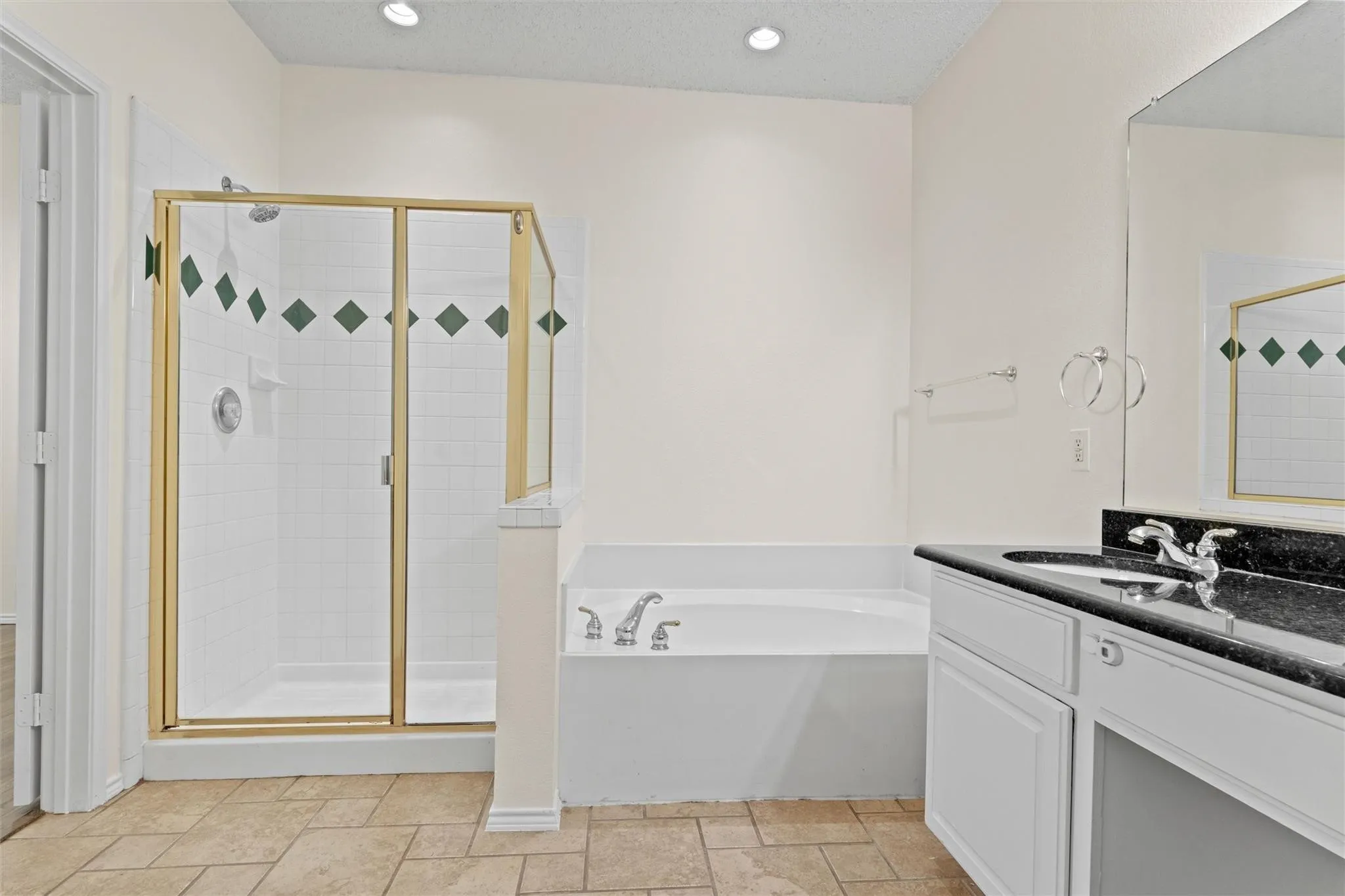 Recessed lighting, integrated bathtub, shower with framed glass enclosure, vanity with dark countertop, and rectangular floor tiles