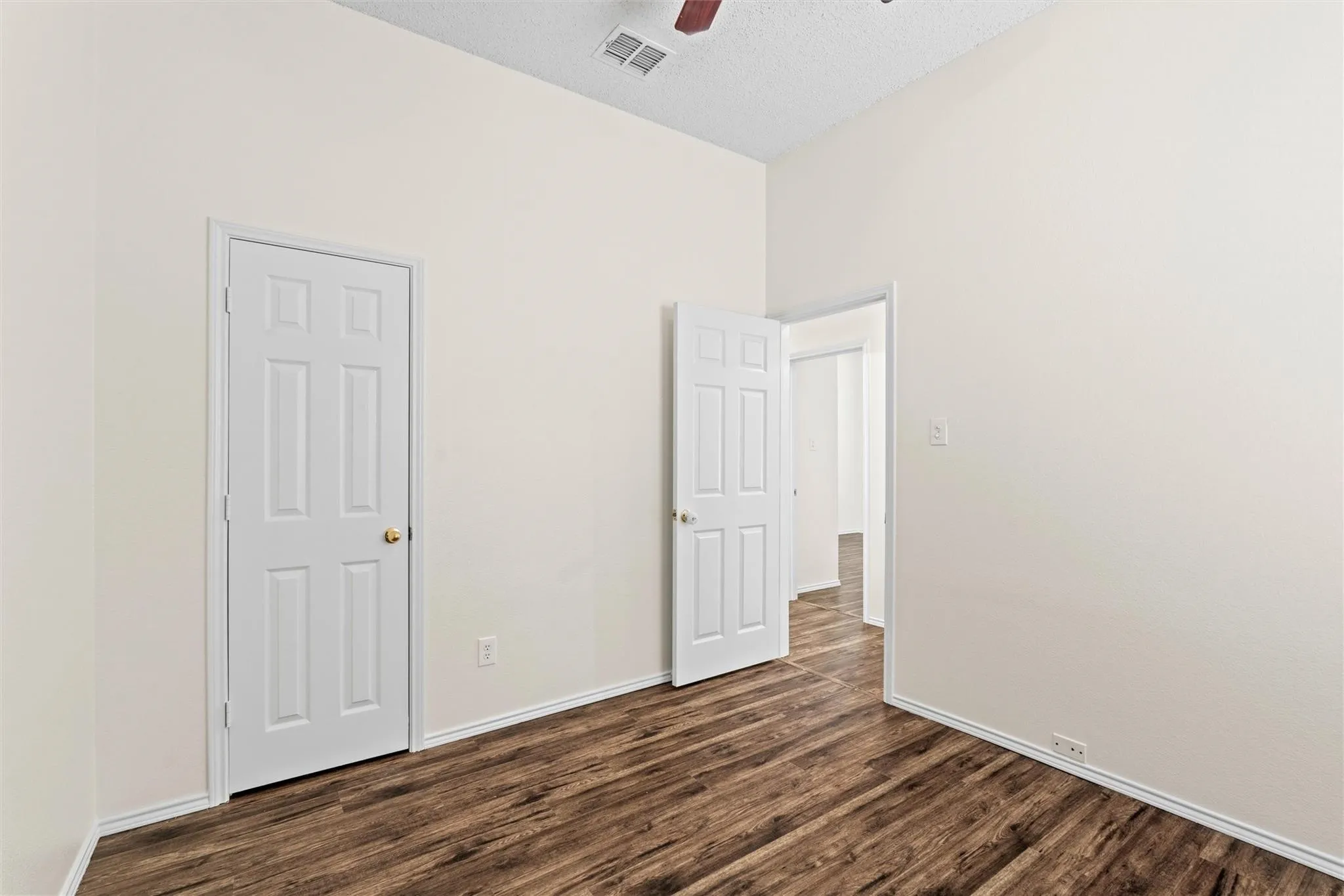 Vaulted ceiling, wood-finish flooring, paneled interior doors, and neutral wall paint