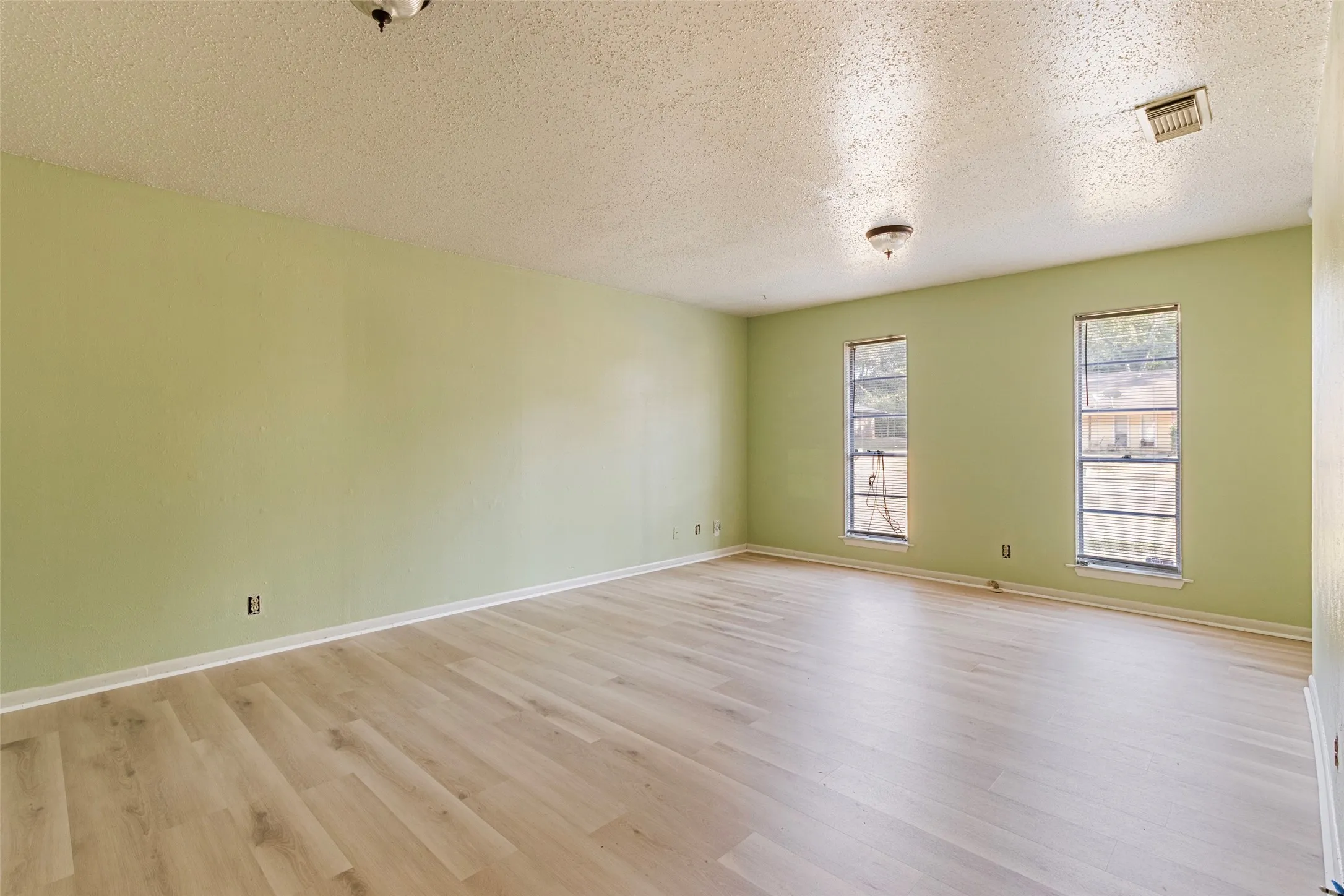 Light wood-finish flooring with a neutral wall color and two windows