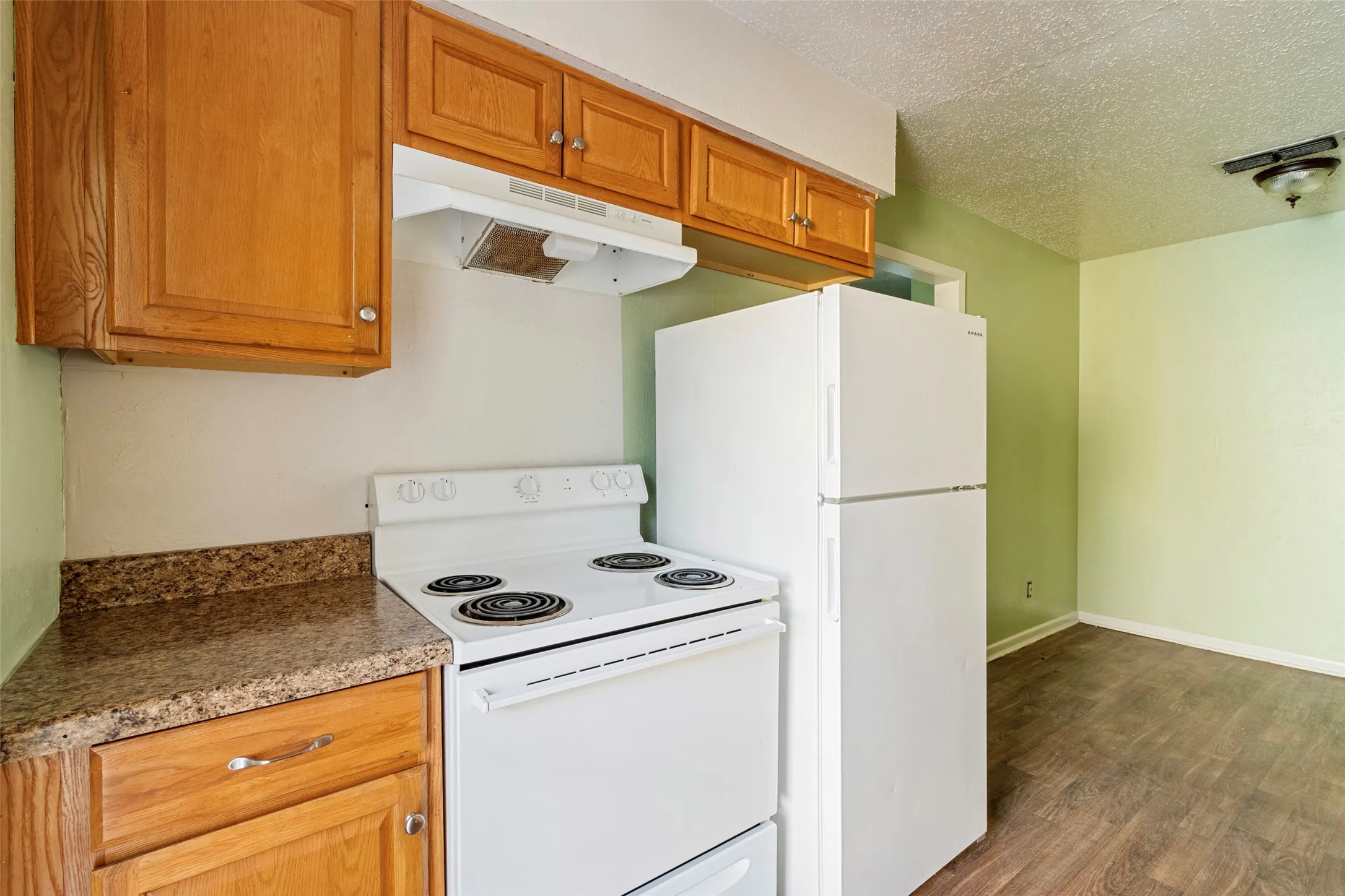 Kitchen featuring wood cabinetry, white electric range, white top-freezer refrigerator, and wood-finish flooring