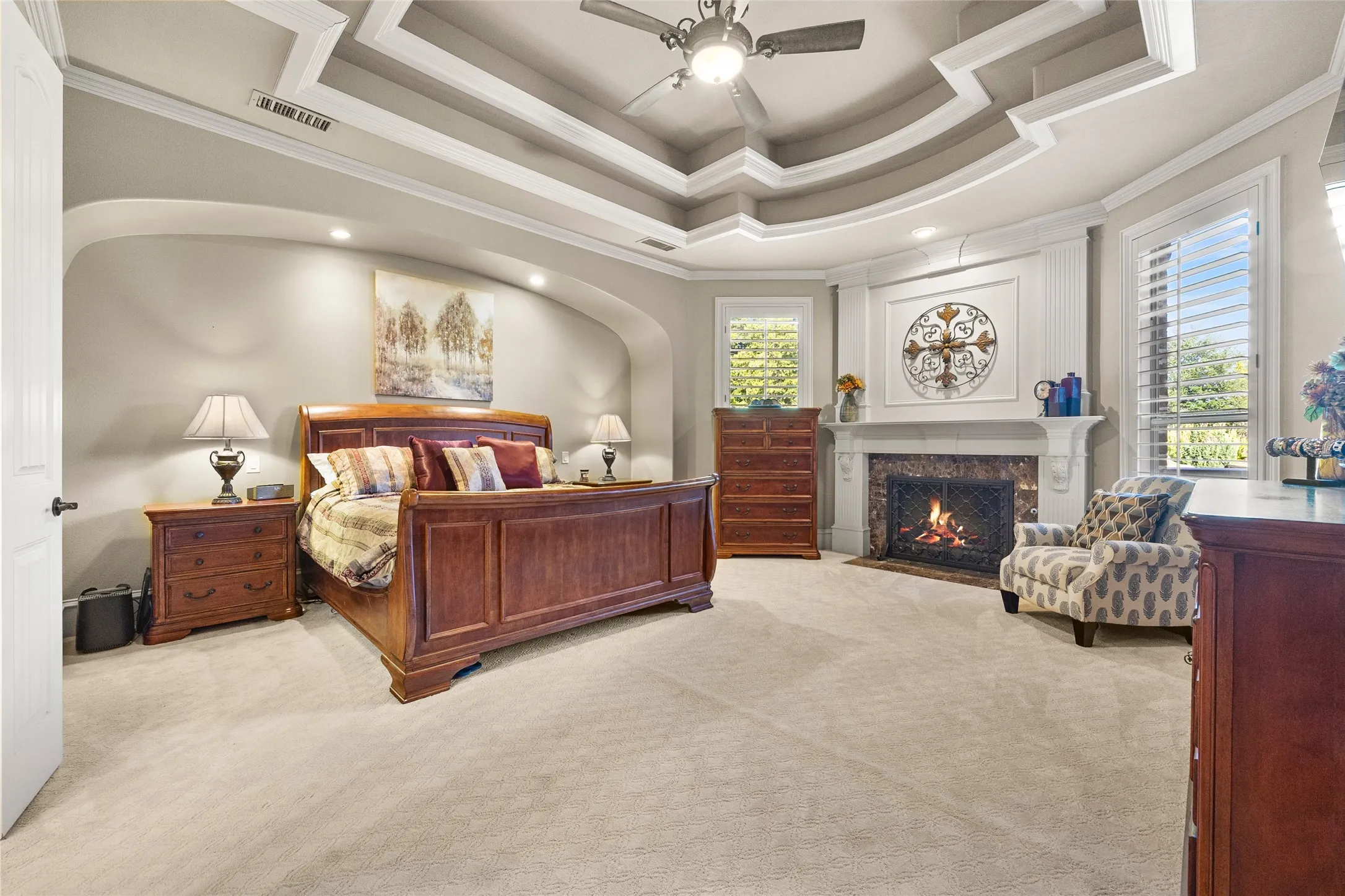 Large primary suite with tray ceilings and a fireplace