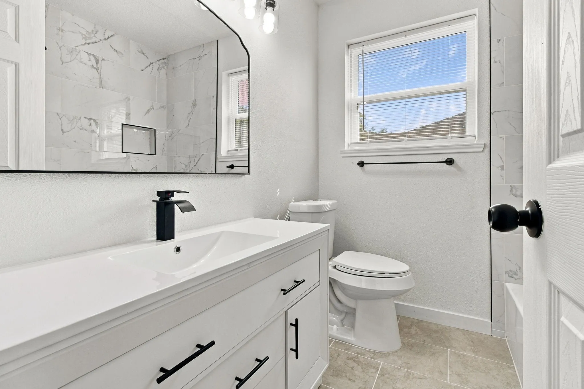 White vanity with matte black hardware, integrated sink, and waterfall faucet
