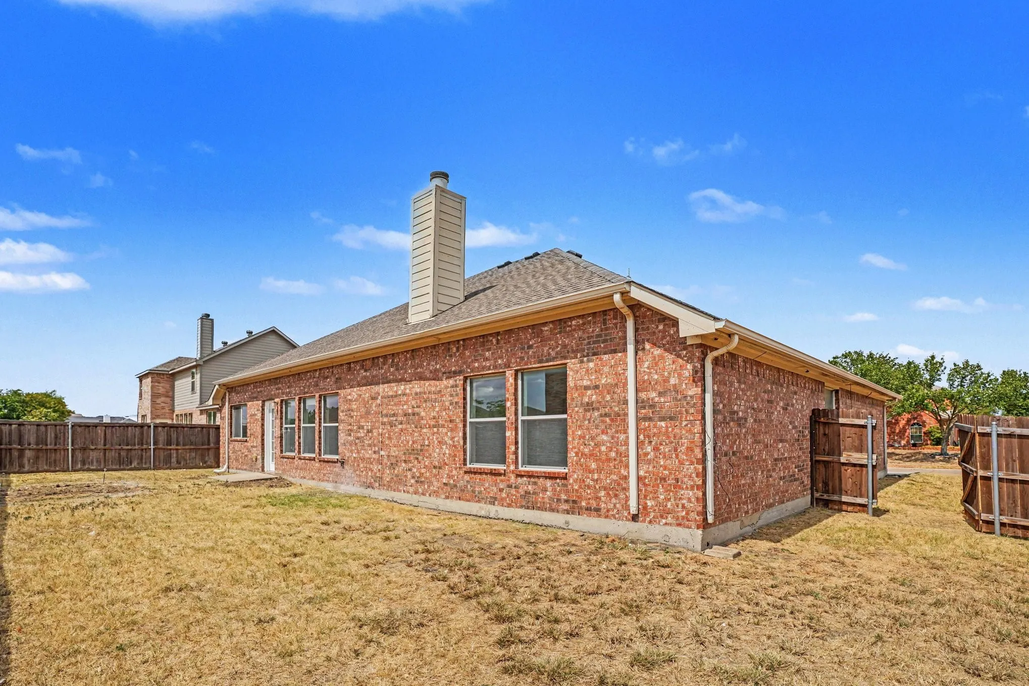 Red brick exterior with multiple windows, pitched shingle roof, and a prominent chimney