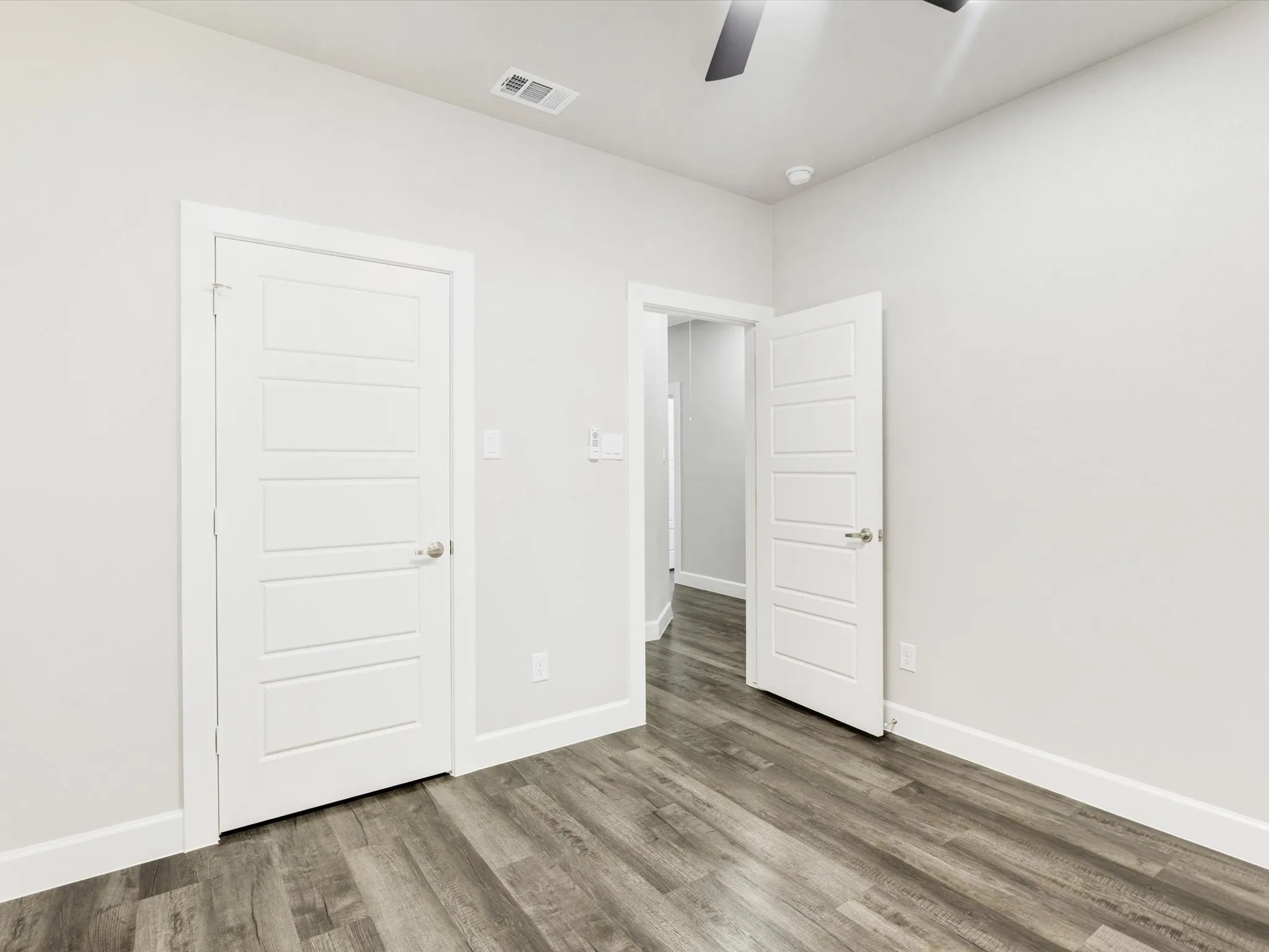 Wood-finish flooring throughout, white walls, and modern panel doors