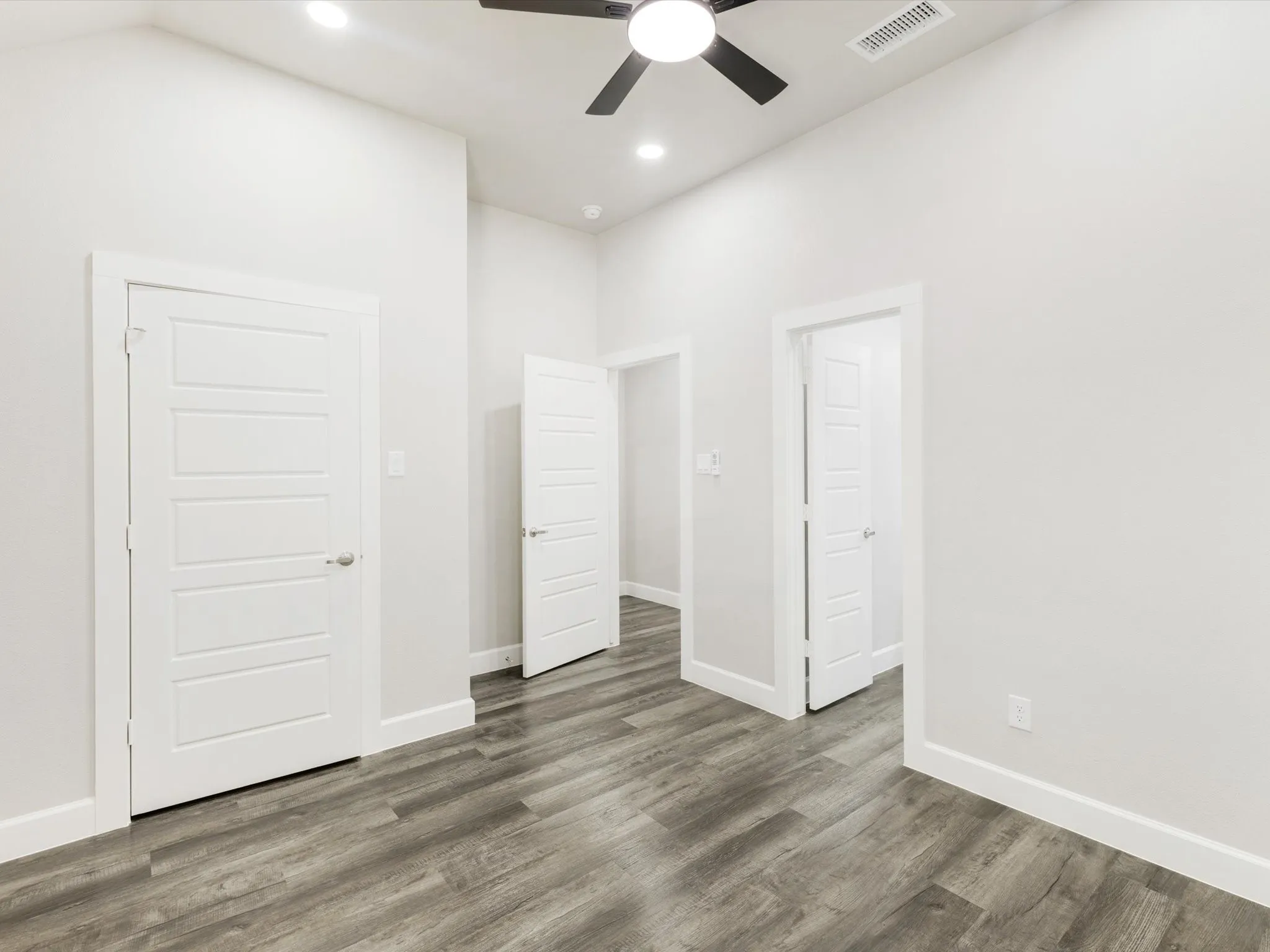 Vaulted ceiling with recessed lighting, ceiling fan, wood-finish flooring, and crisp white trim