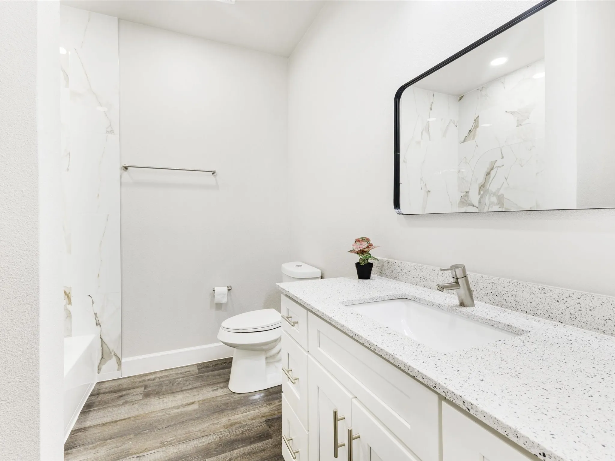 White vanity with brushed nickel hardware, integrated sink, and speckled countertop