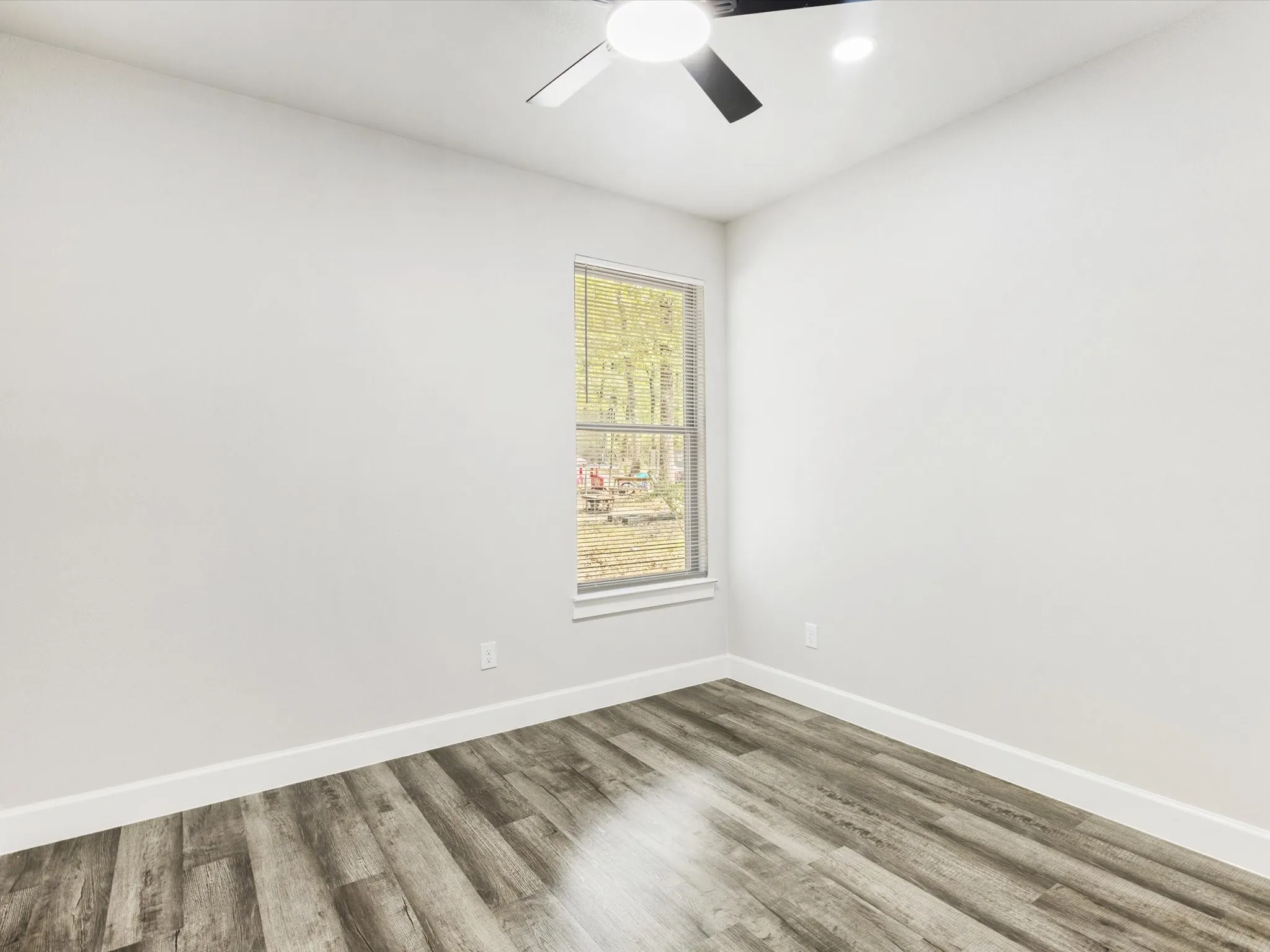 Wood-finish flooring, white walls, and a ceiling fan with integrated lighting
