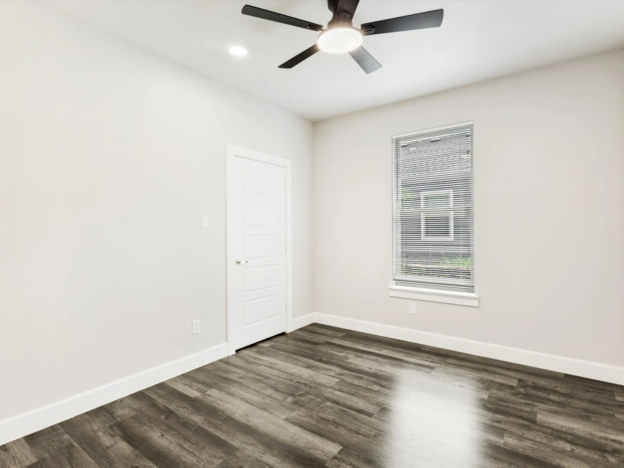 Wood-finish flooring with white baseboards and neutral wall paint