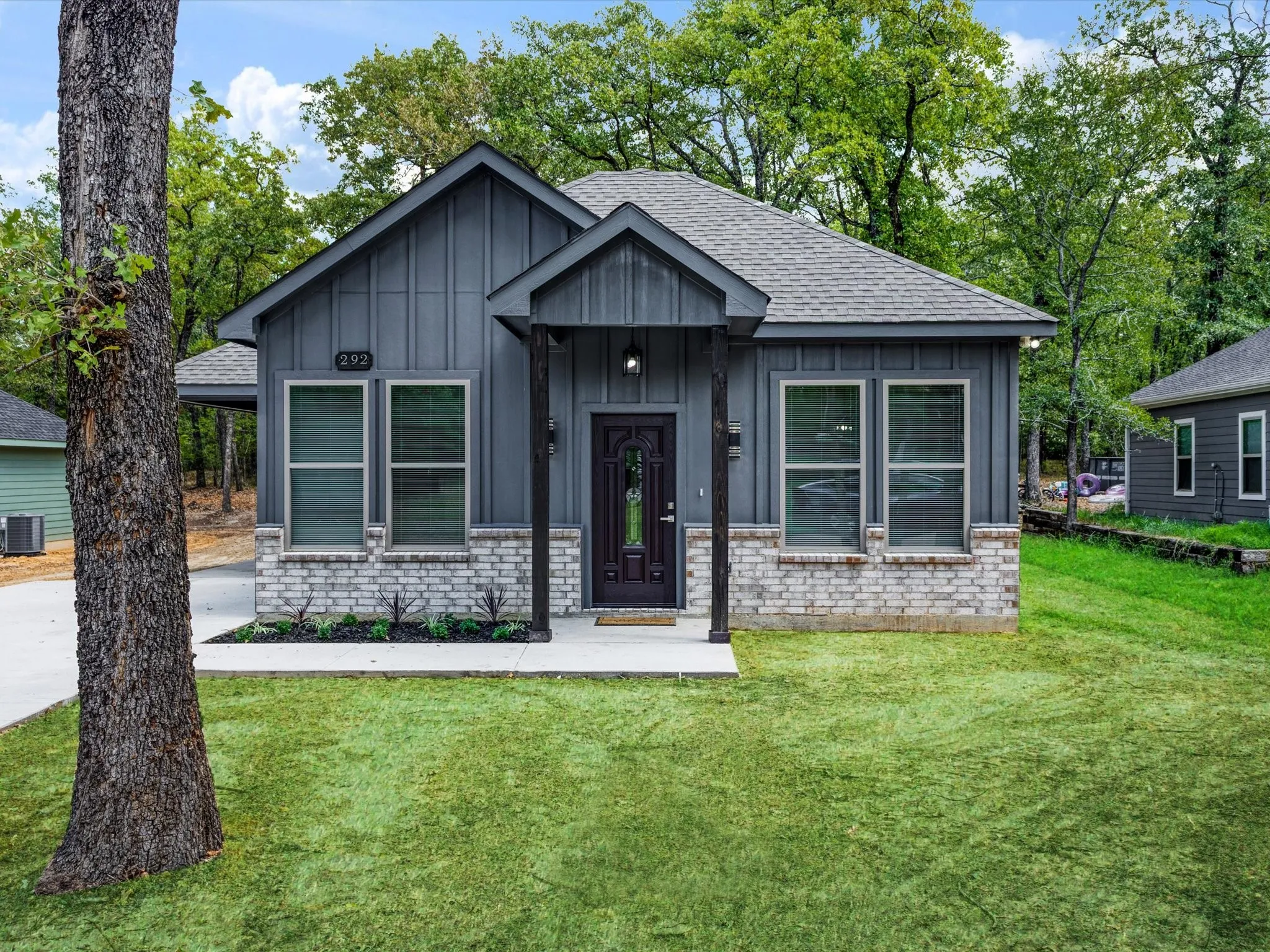 Board and batten siding, stone veneer accents, covered entry, front yard, and concrete walkway