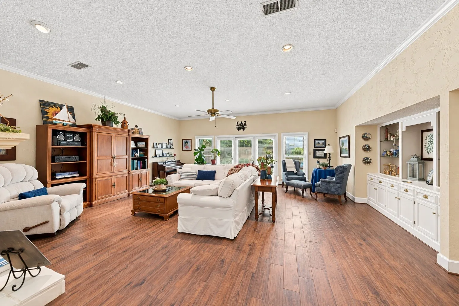 Expansive living area with wood-finish flooring, recessed lighting, and crown molding