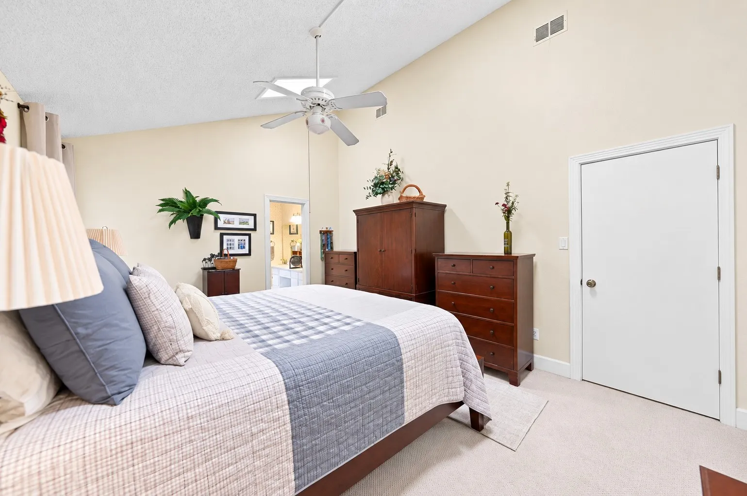 Vaulted ceiling with skylight and ceiling fan, neutral wall tones, and light-toned carpeting