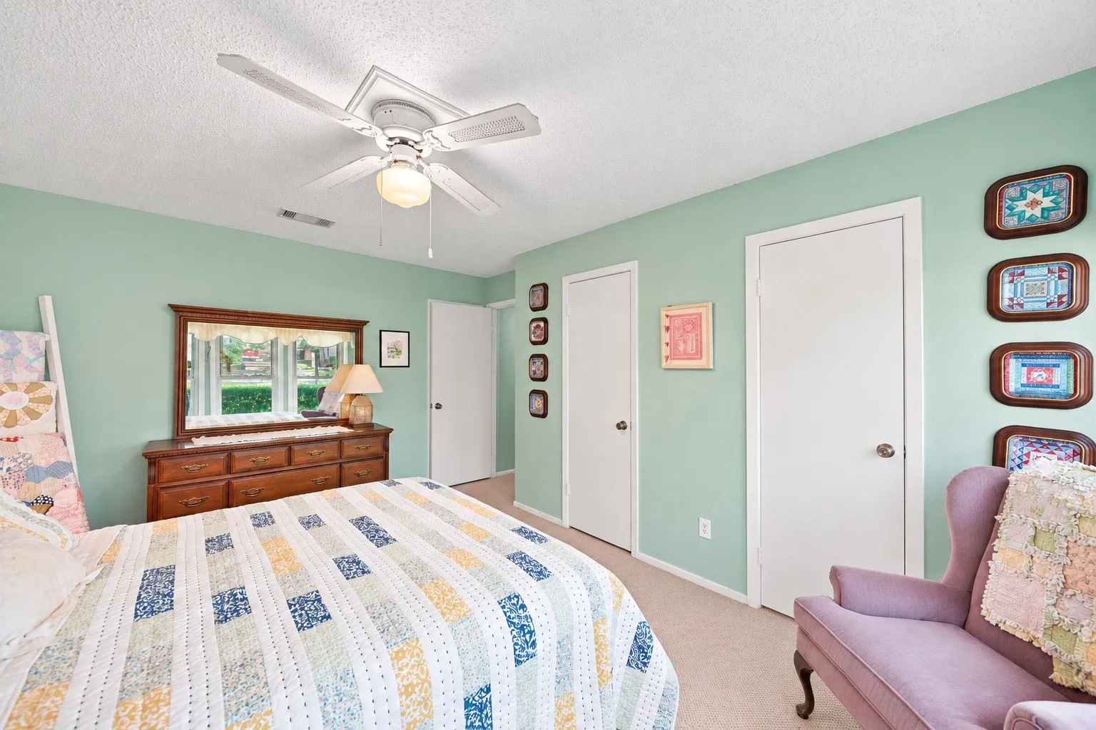 Ceiling fan with integrated lighting, two white panel doors, and neutral carpeting