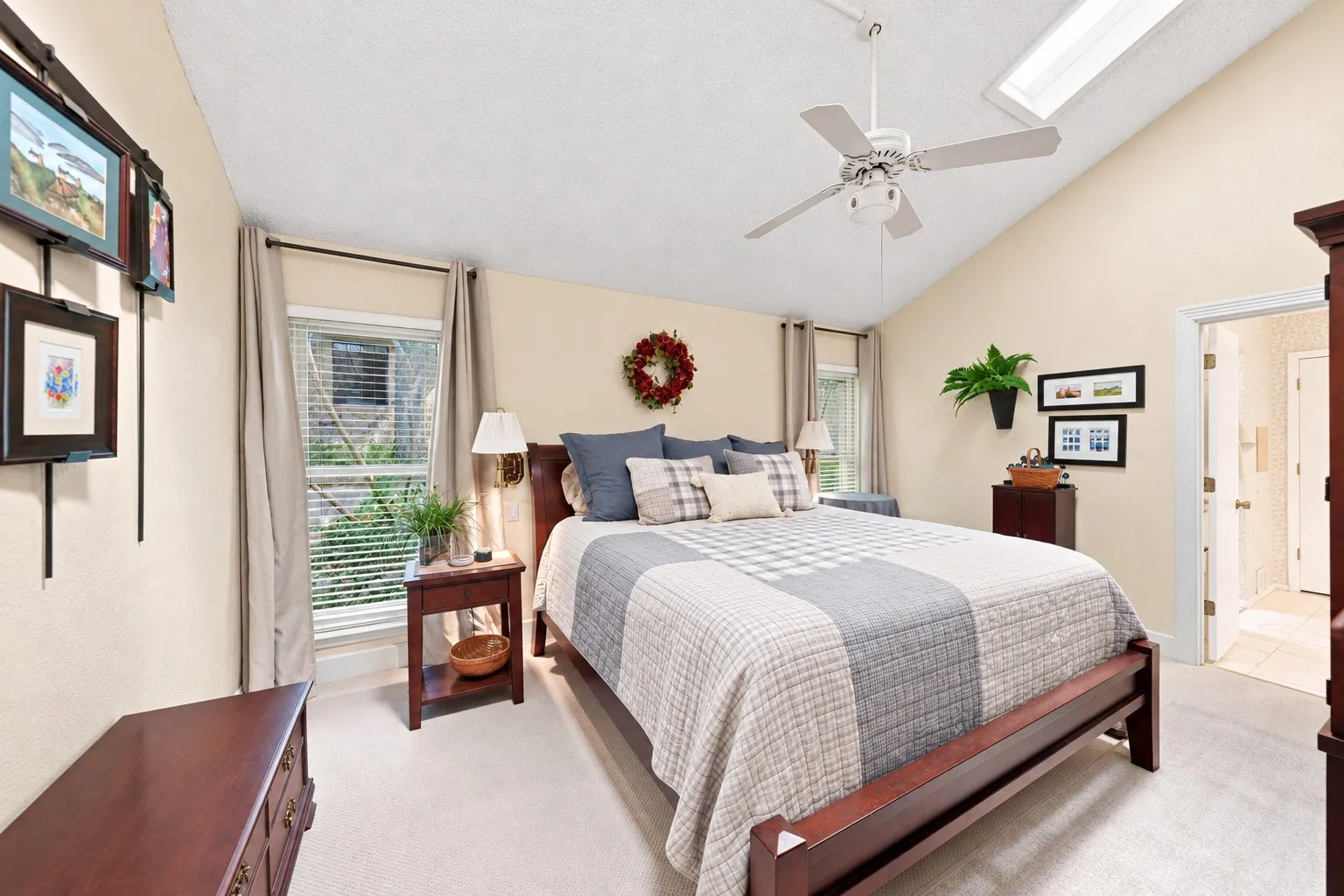 Vaulted ceiling with skylight, ceiling fan, carpeted flooring, and a window with blinds