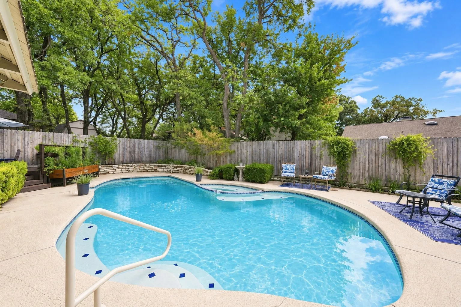 Backyard featuring a free-form swimming pool with integrated spa and stone coping