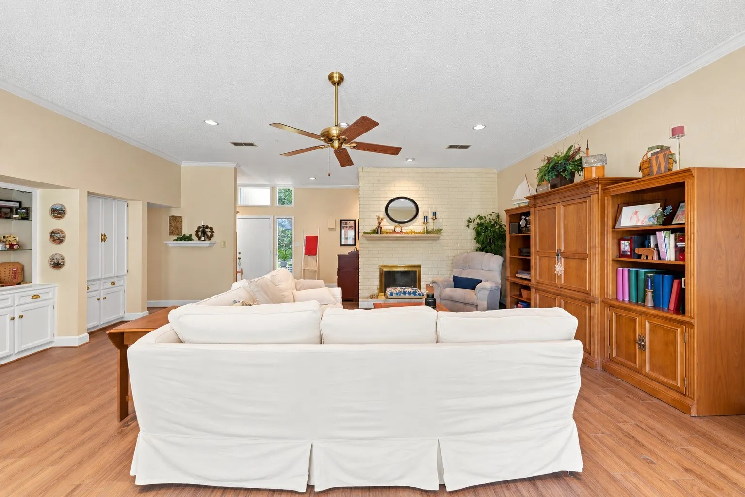 Spacious living area featuring wood-finish flooring, a ceiling fan with integrated lighting, and recessed lighting