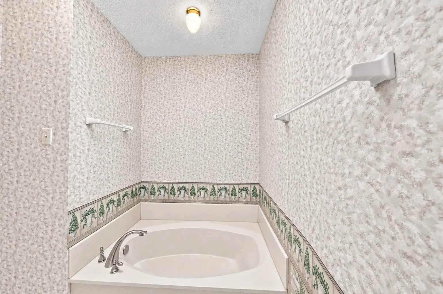 Built-in soaking tub with a deck-mounted faucet and a decorative tiled border