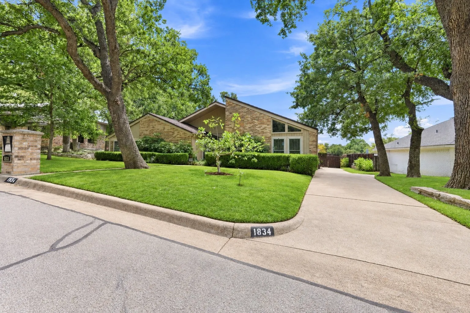 Mid-century modern brick exterior with a low-sloped roofline, front-facing gabled windows, and a manicured lawn