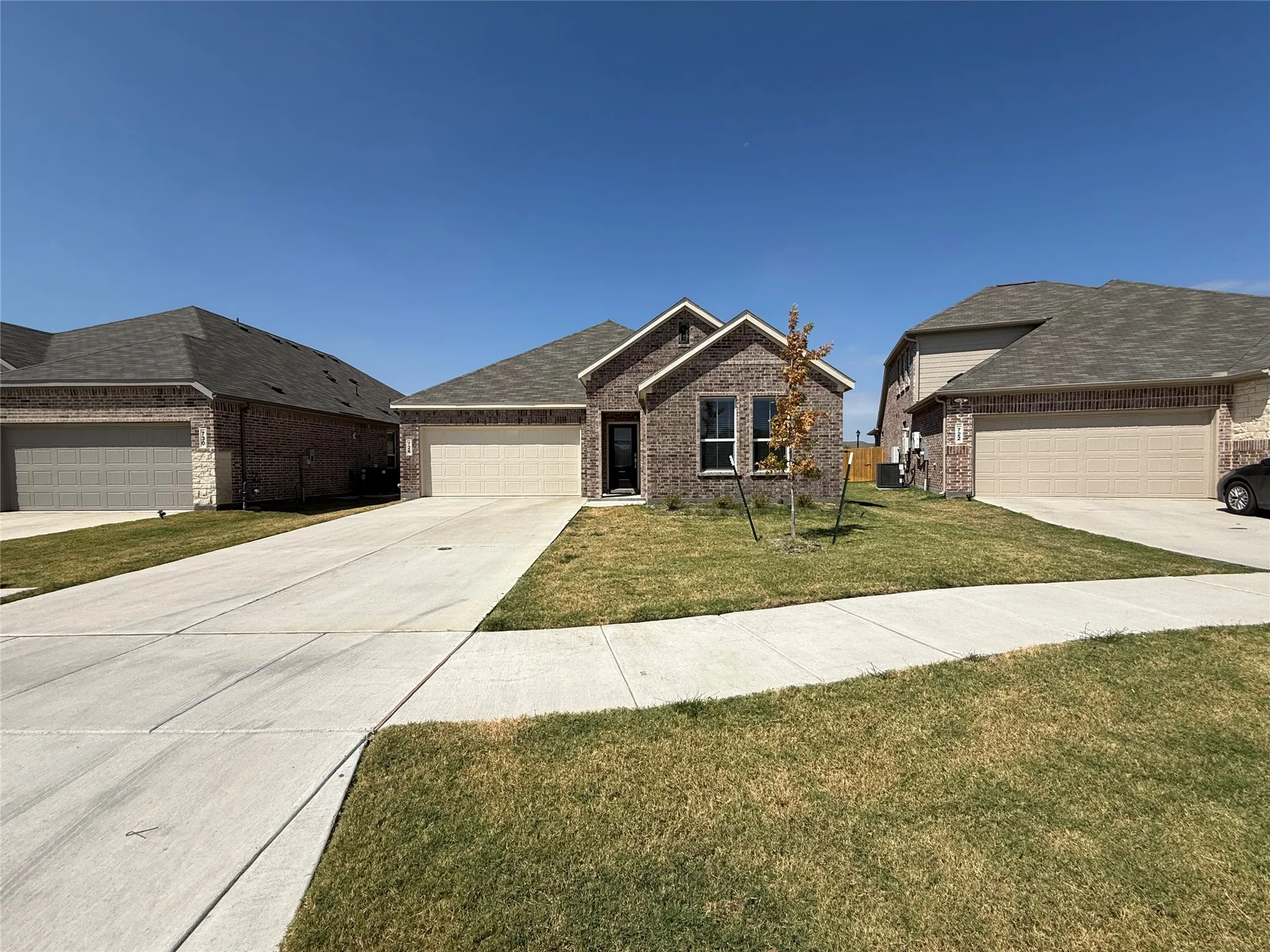 Brick exterior with an attached garage, concrete driveway, and covered entryway