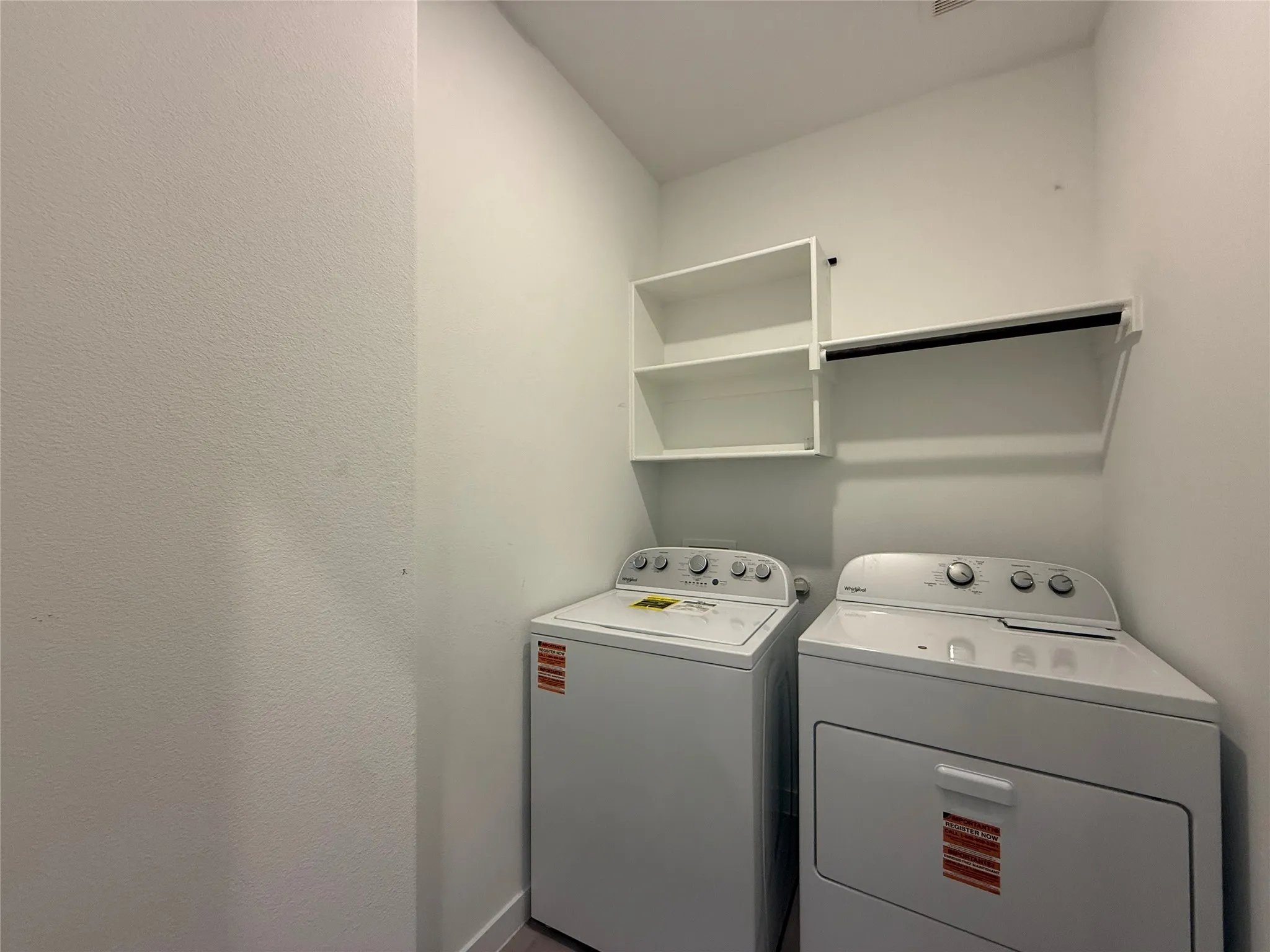 Laundry area featuring white walls, open shelving, and a hanging rod