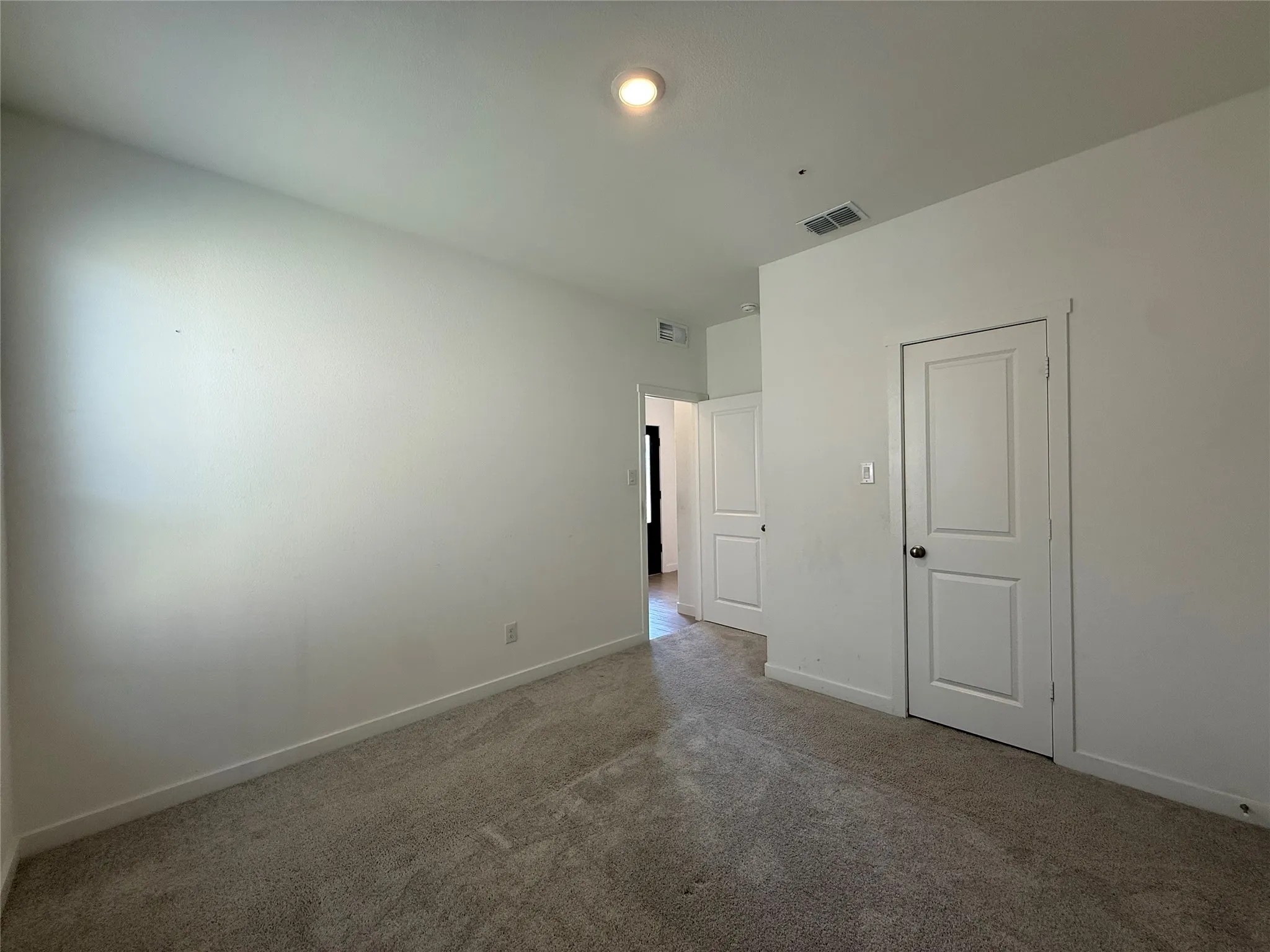 Carpeted flooring with white wall finishes, featuring a flush-mount ceiling light